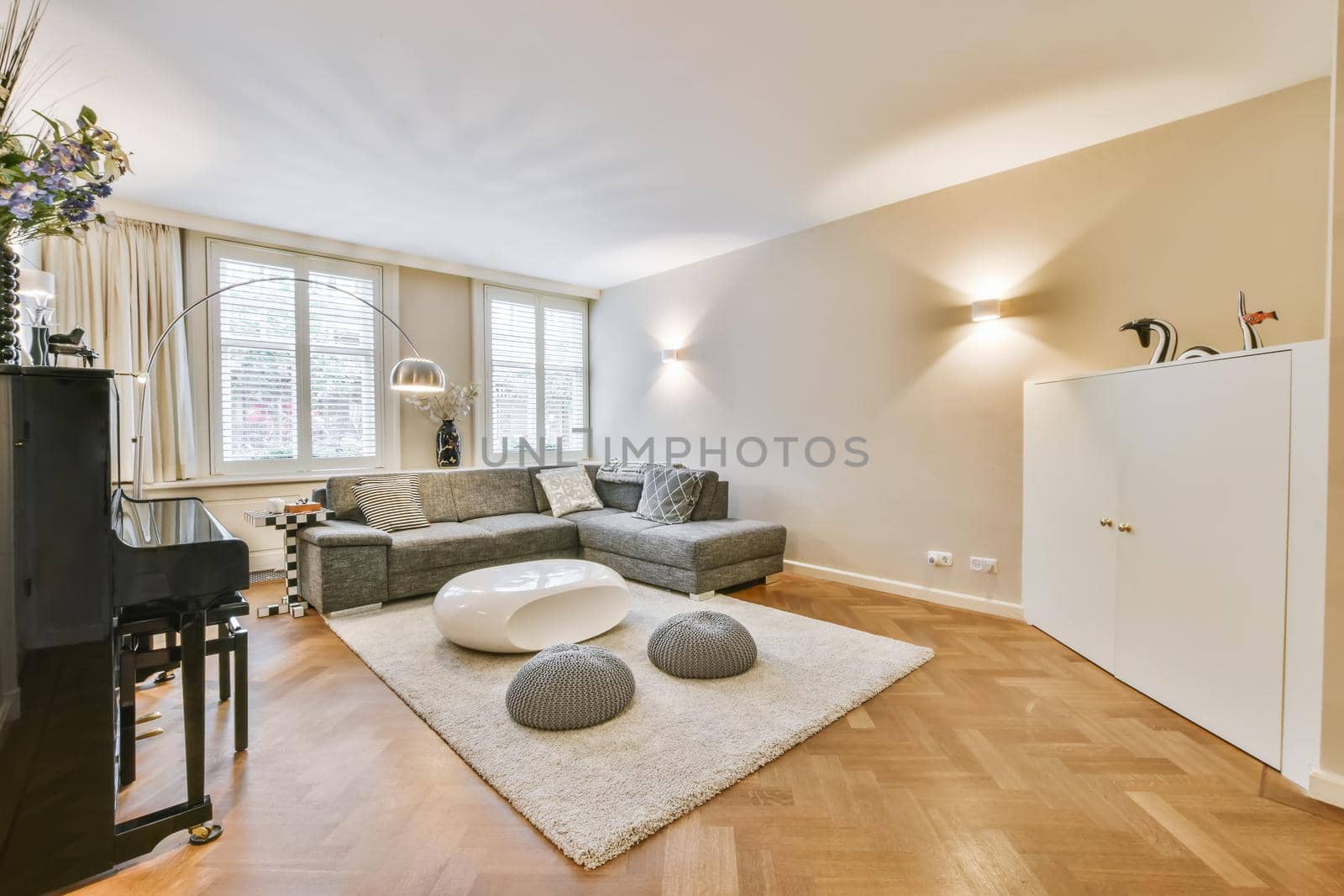 Comfortable sofa and armchair placed on soft carpet near windows in cozy light living room in modern flat