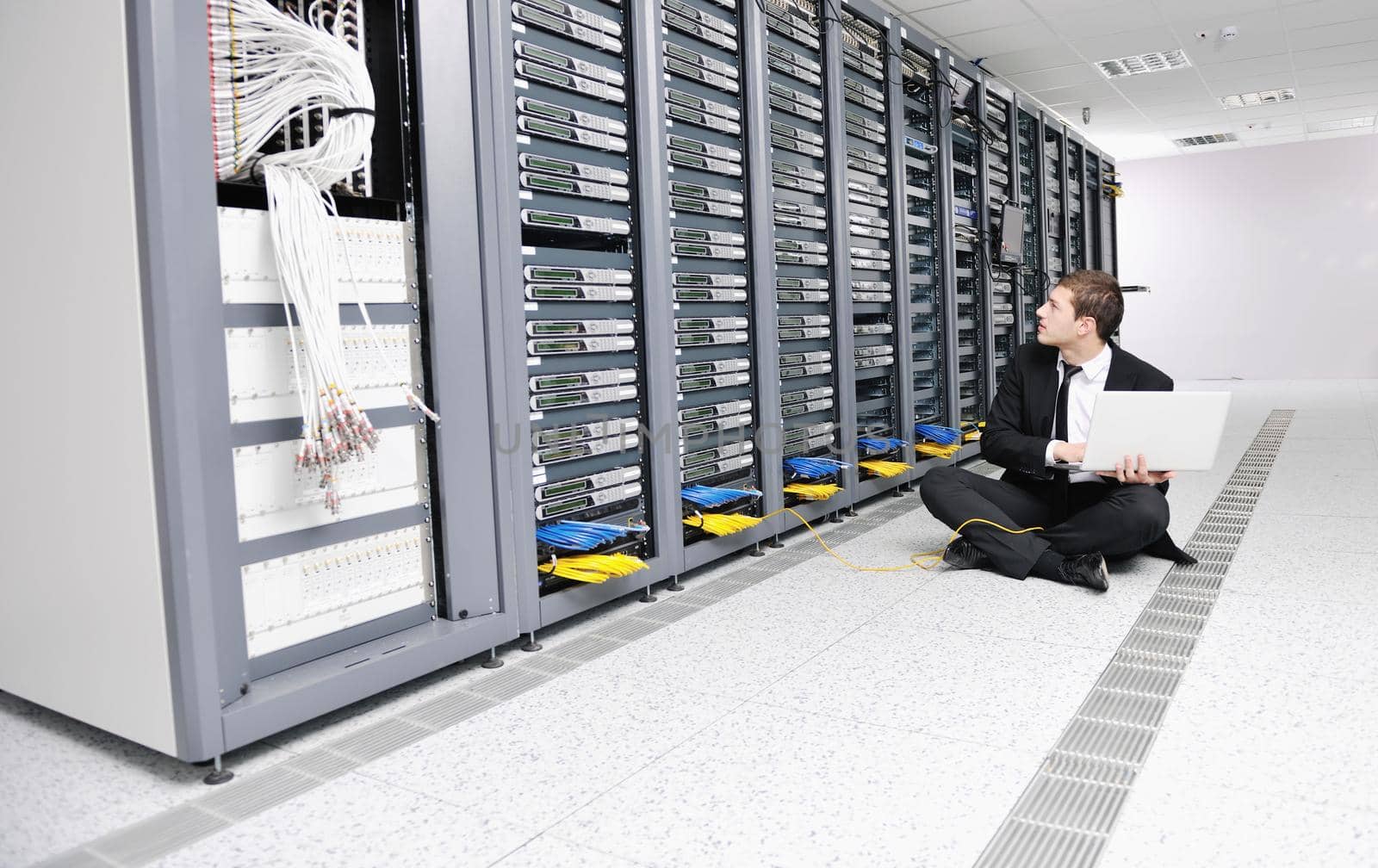 businessman with laptop in network server room by dotshock