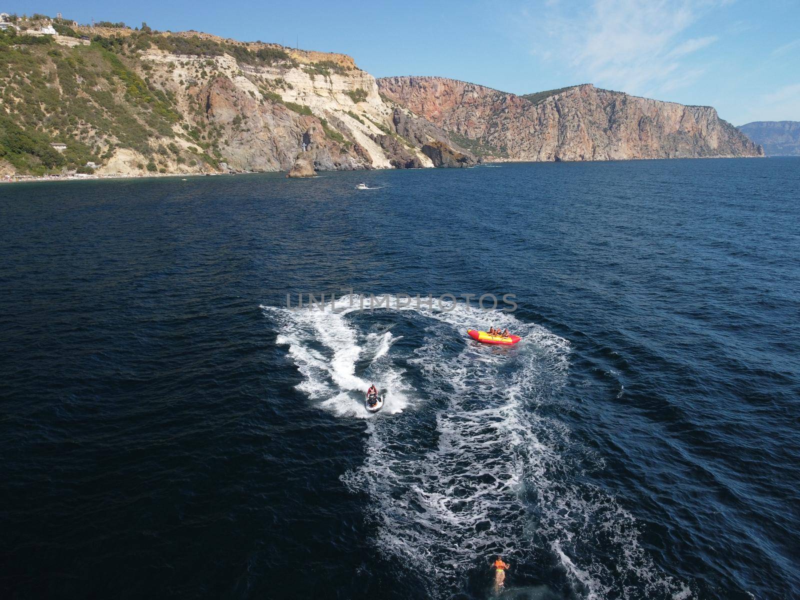 Inflatable attraction. Happy people are going to swim on an air mattress behind a jet ski. Tourists ride the inflatable watercraft boat. Jet ski skating people on a large Inflatable raft