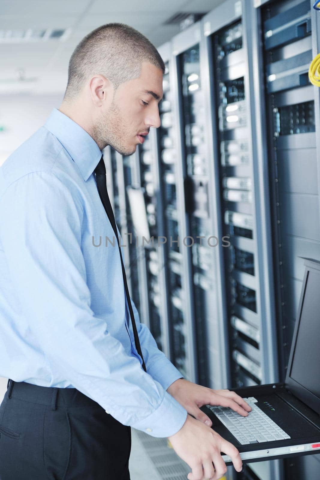 young it engineer in datacenter server room by dotshock