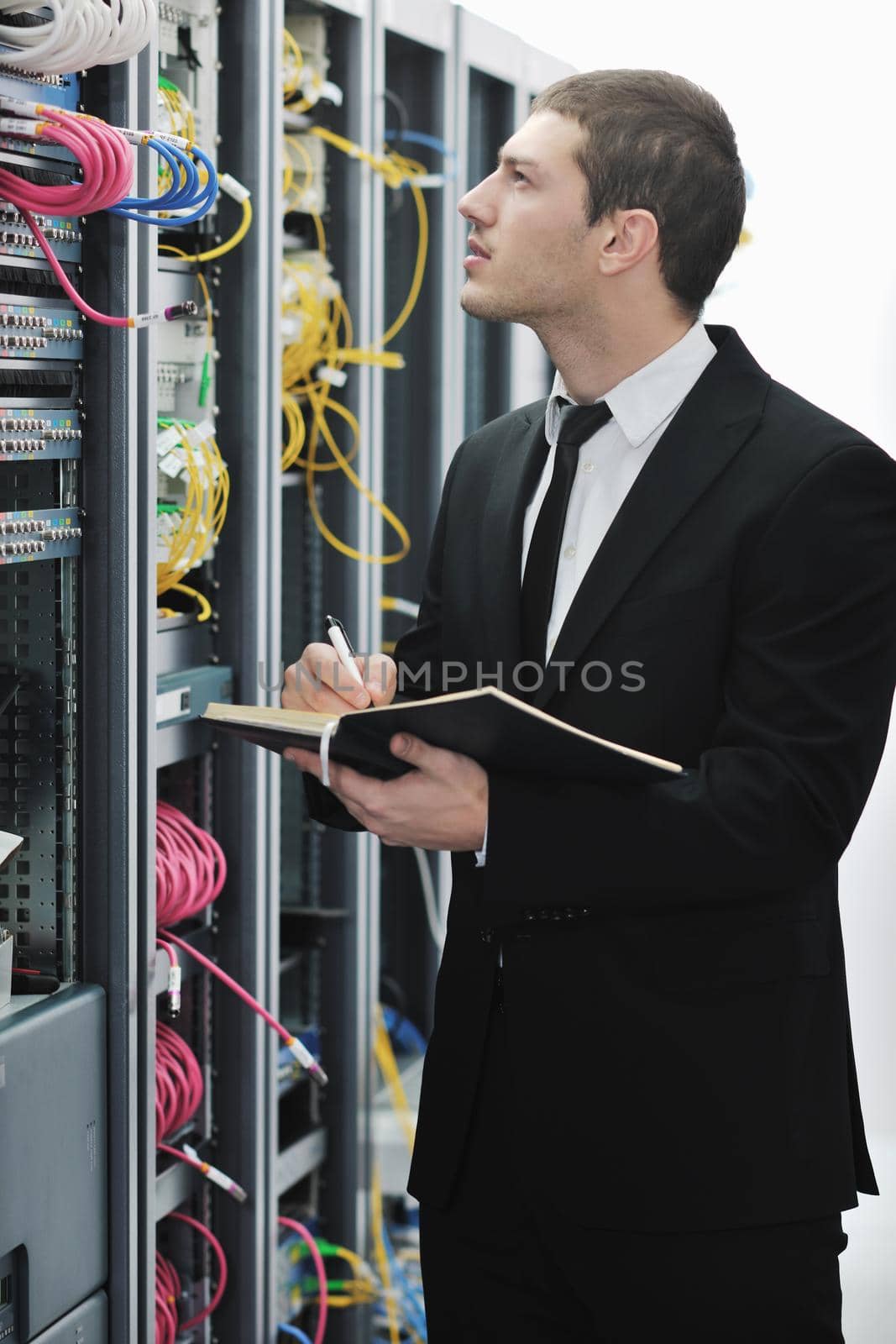 young engeneer business man with notebook  in network server room