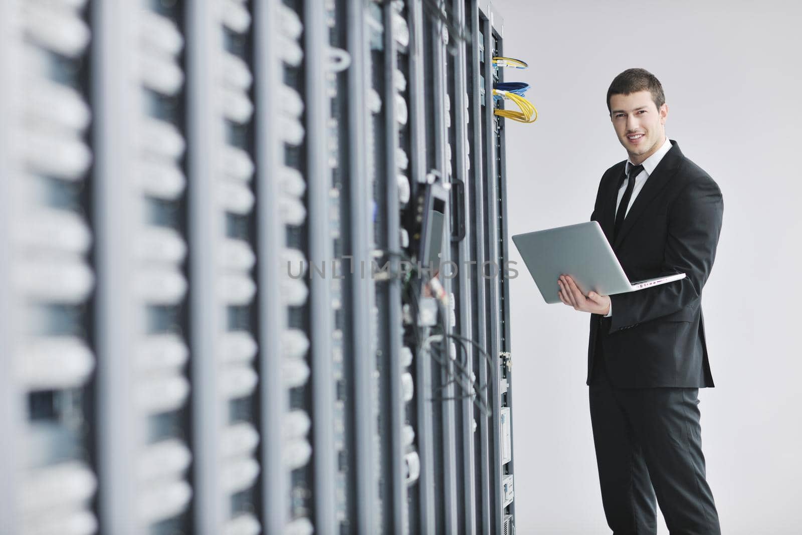 businessman with laptop in network server room by dotshock