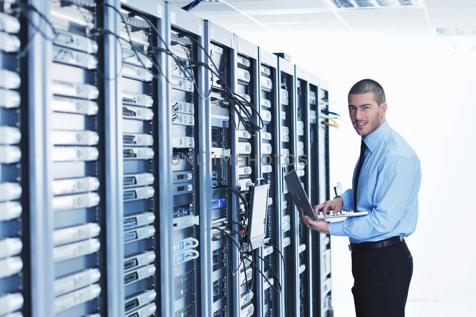 businessman with laptop in network server room by dotshock