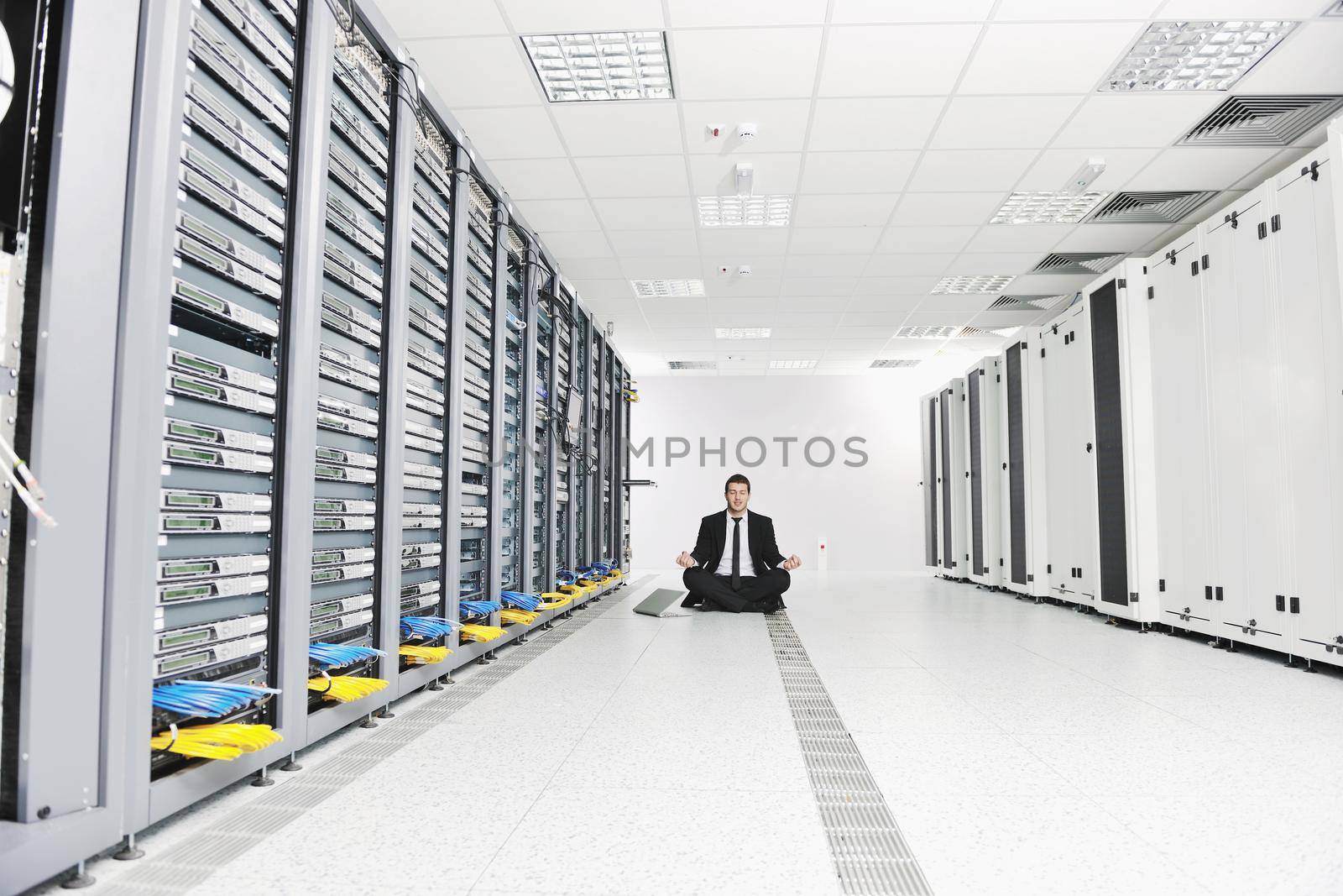 young handsome business man in black suit and tie practice yoga and relax at network server room while representing stres control concept