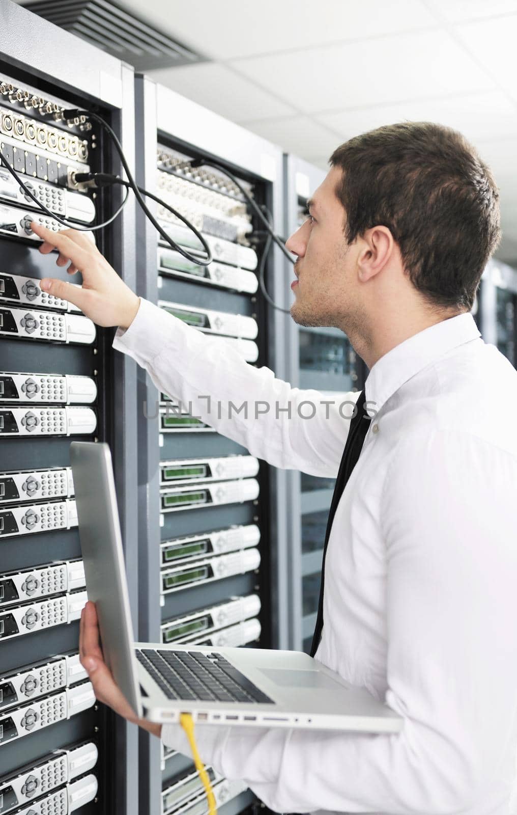 businessman with laptop in network server room by dotshock