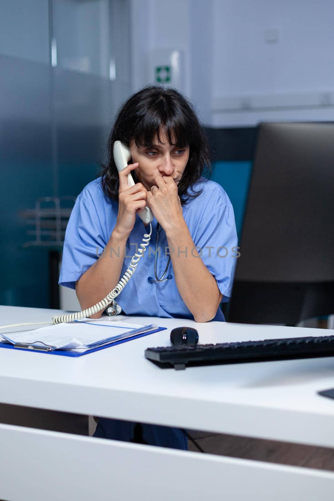 Medical assistant talking on landline phone to patient by DCStudio