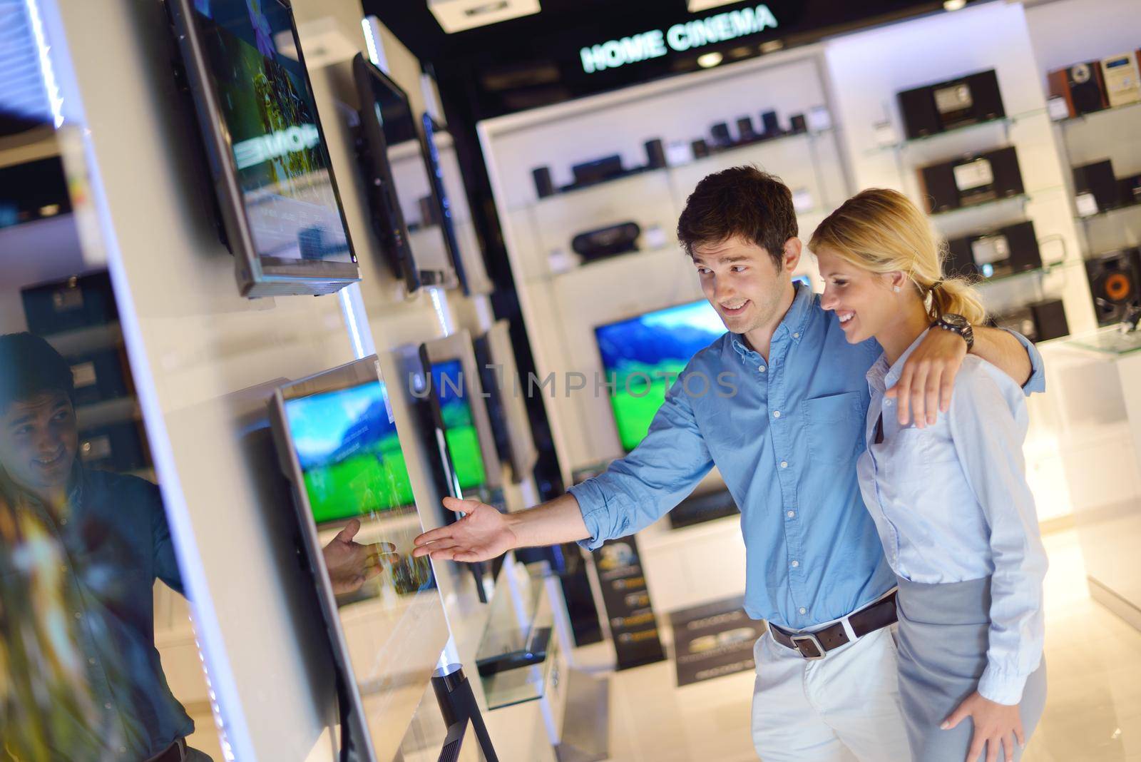 people in consumer electronics  retail store looking at latest laptop, television and photo camera to buy