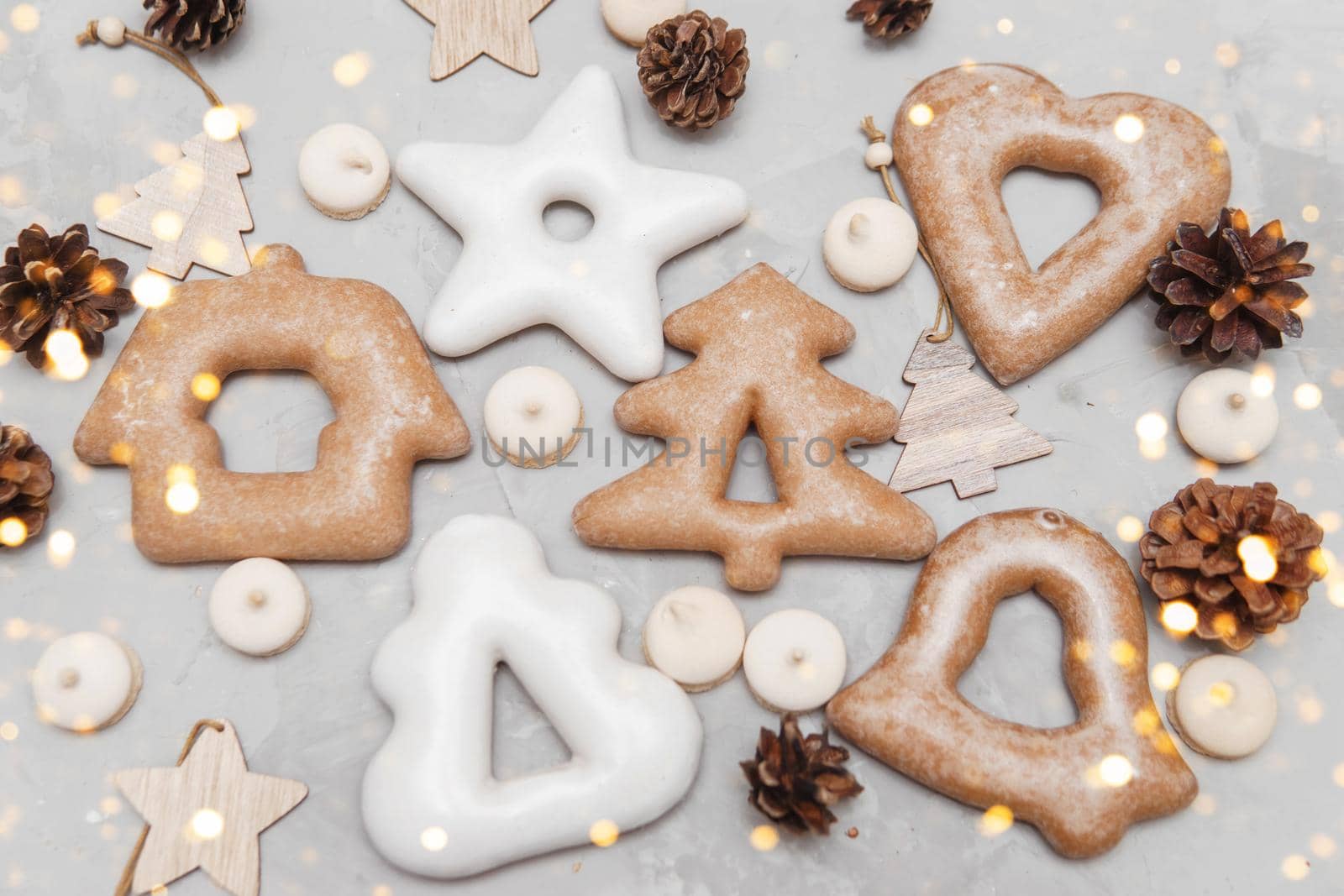 Banner for Christmas and New Year gingerbread stars, houses, Christmas trees, toys on a gray concrete background, Christmas lights bokeh in the foreground.
