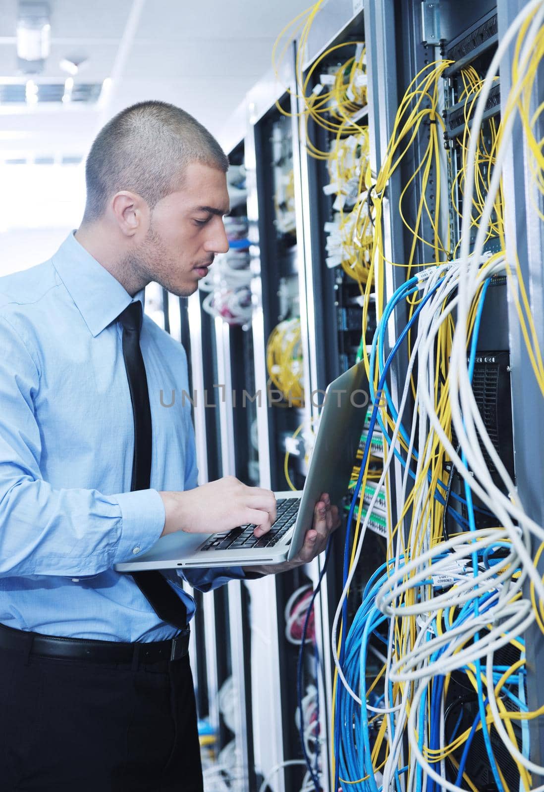 young engeneer business man with thin modern aluminium laptop in network server room