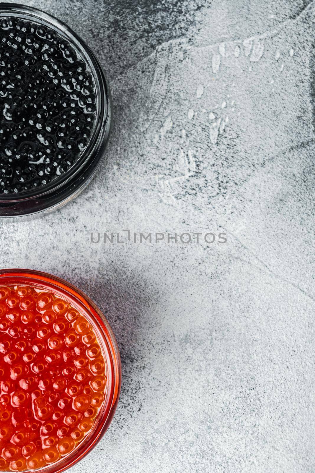 Red and black caviar in glass bowl, on gray background, top view flat lay with copy space for text