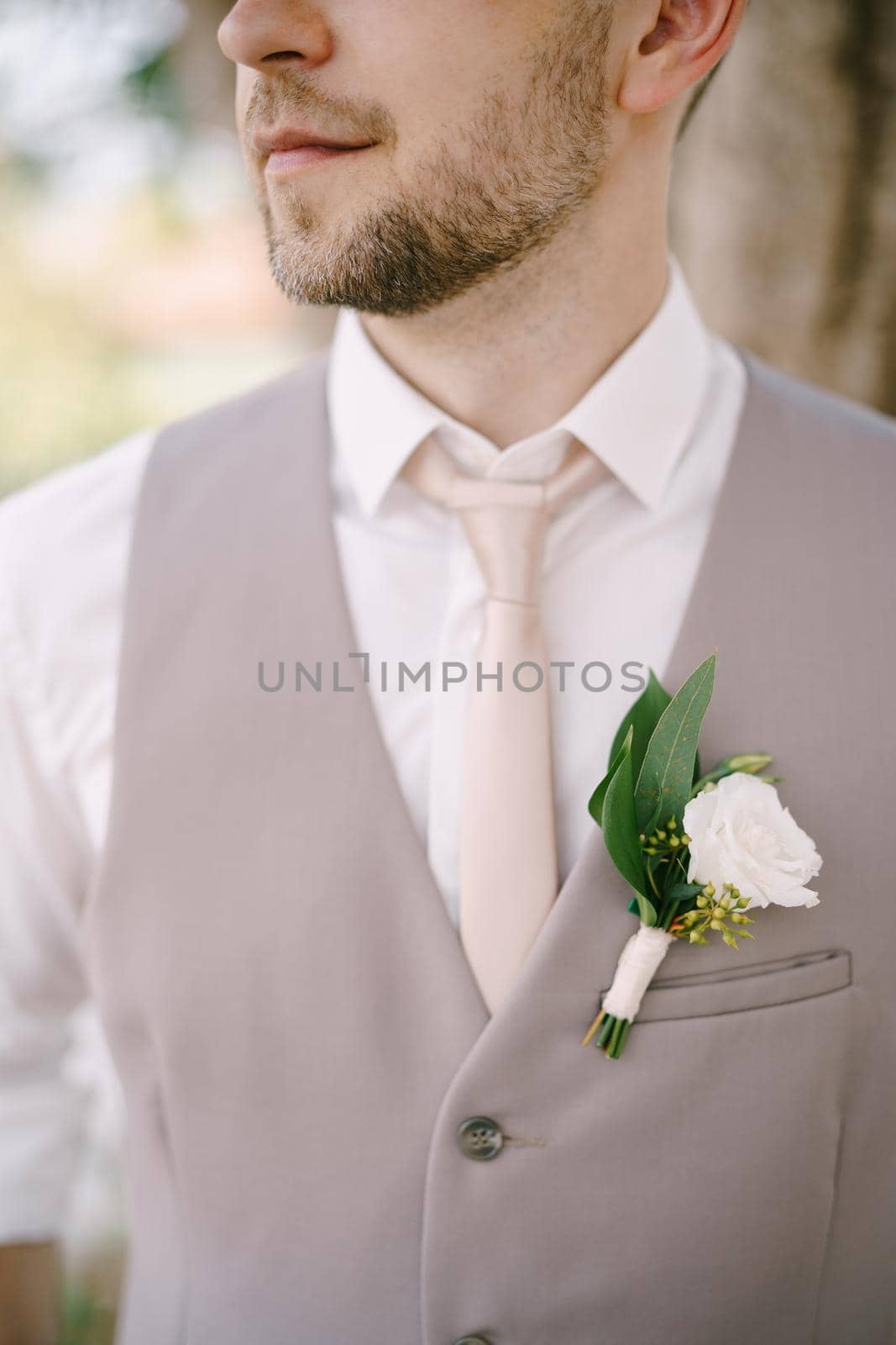 Groom in a white shirt, tie and vest with a boutonniere. Close-up. High quality photo