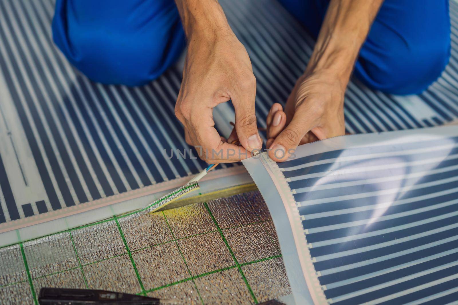 Master installs film warm floor in the room. Floor heating installation by galitskaya