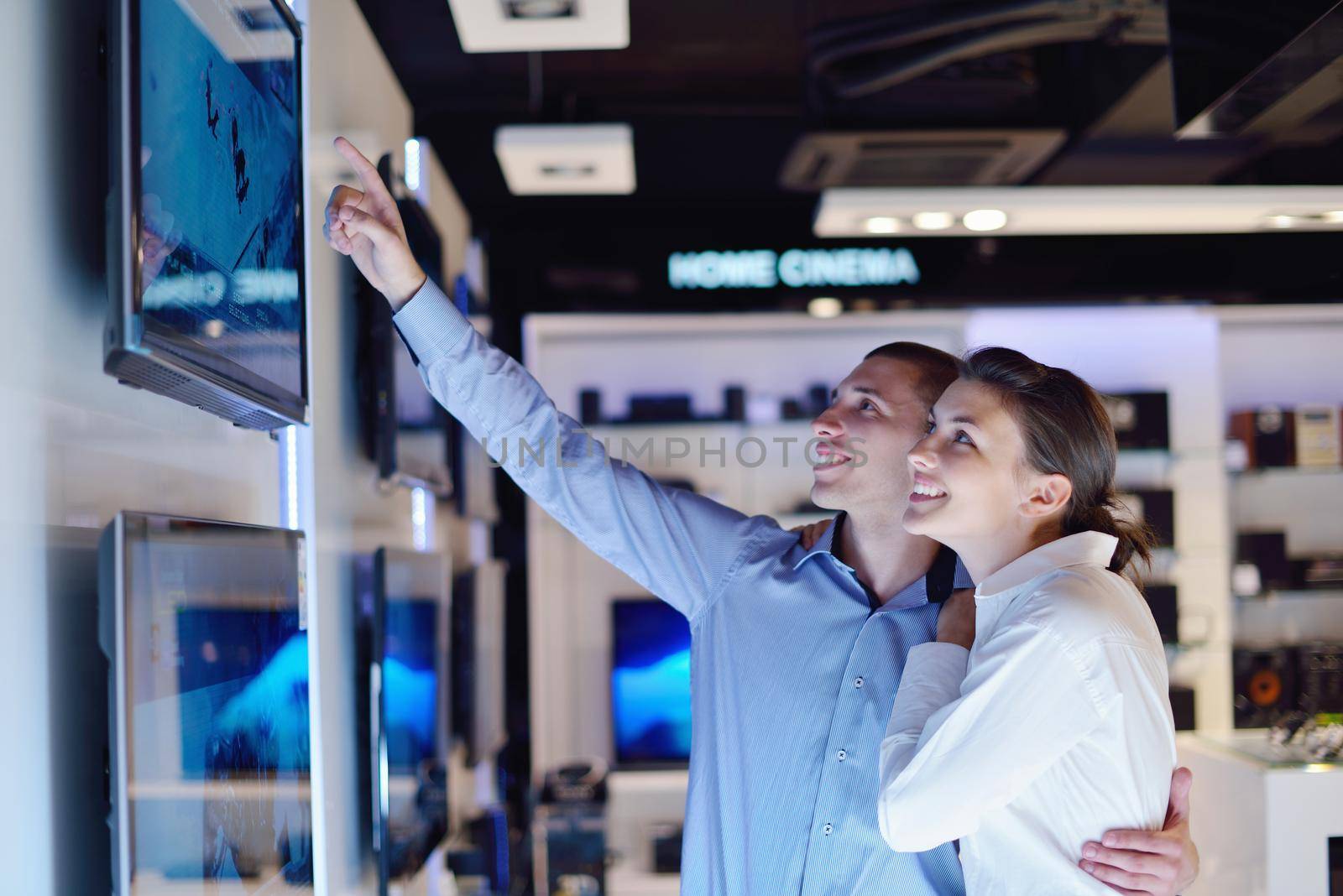 people in consumer electronics  retail store looking at latest laptop, television and photo camera to buy