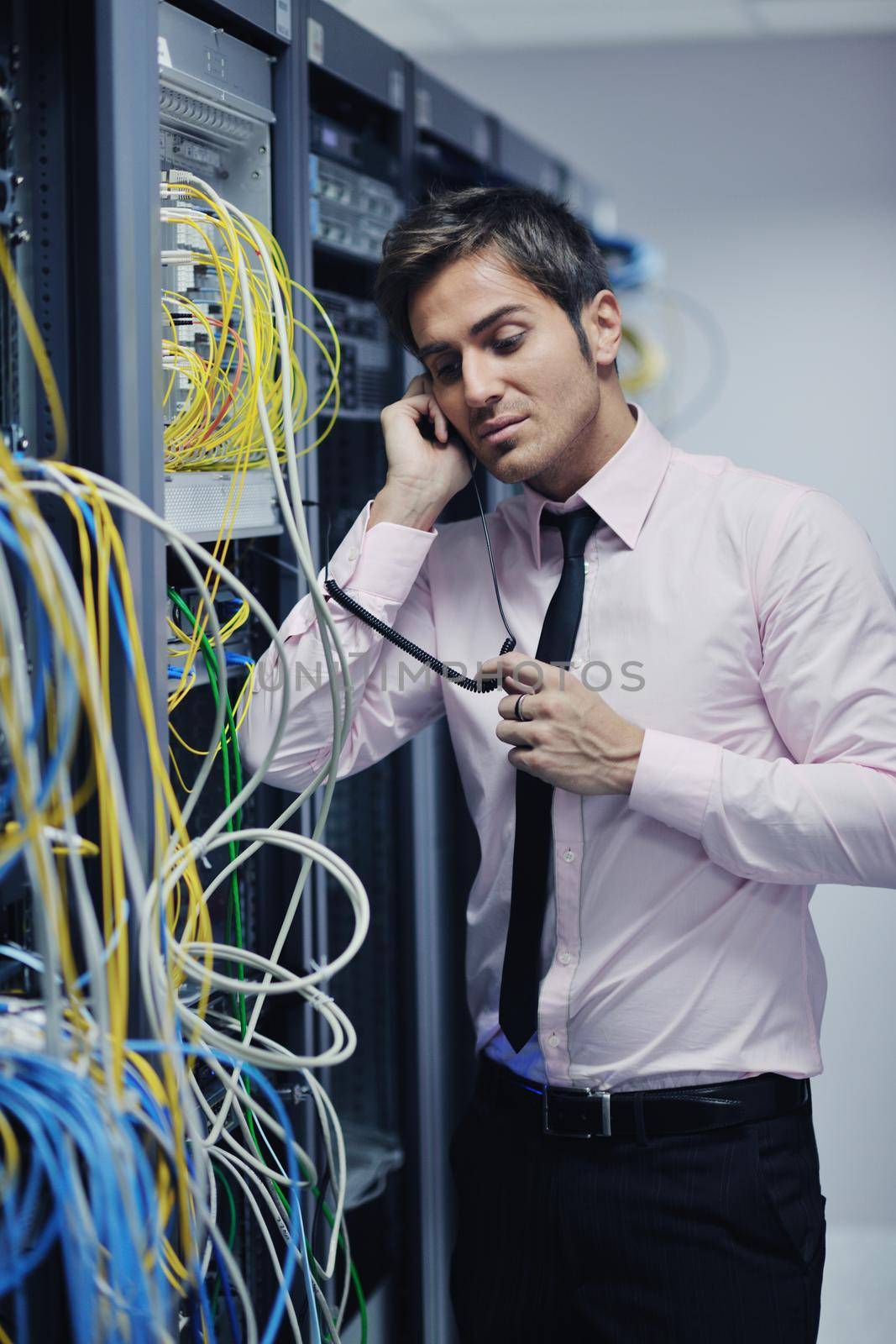 young business man computer science engeneer talking by cellphone at network datacenter server room asking  for help and fast solutions and services