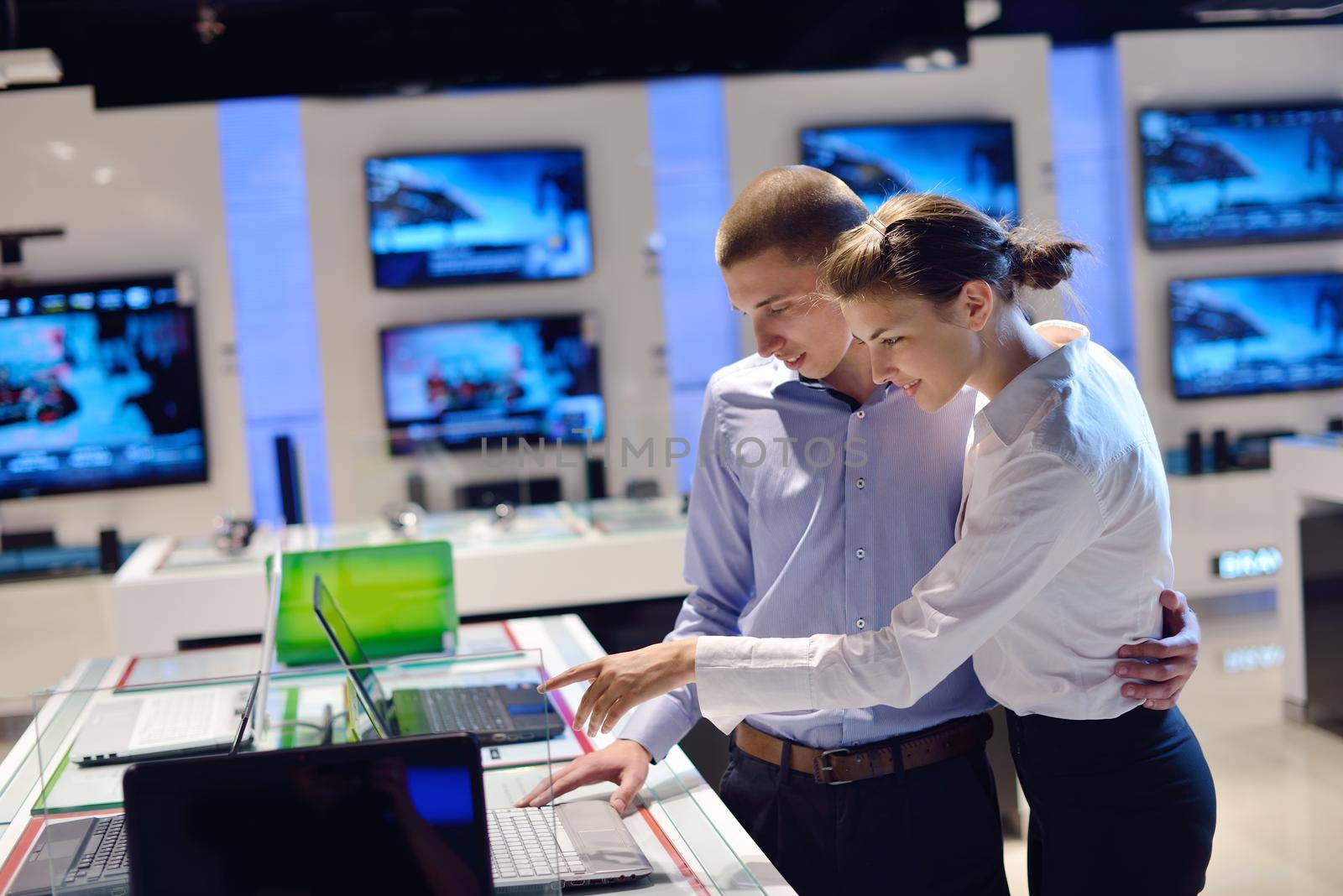 people in consumer electronics  retail store looking at latest laptop, television and photo camera to buy