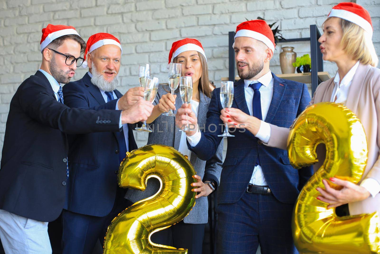 Business people are celebrating holiday in modern office drinking champagne and having fun in coworking. Merry Christmas and Happy New Year 2022. by tsyhun