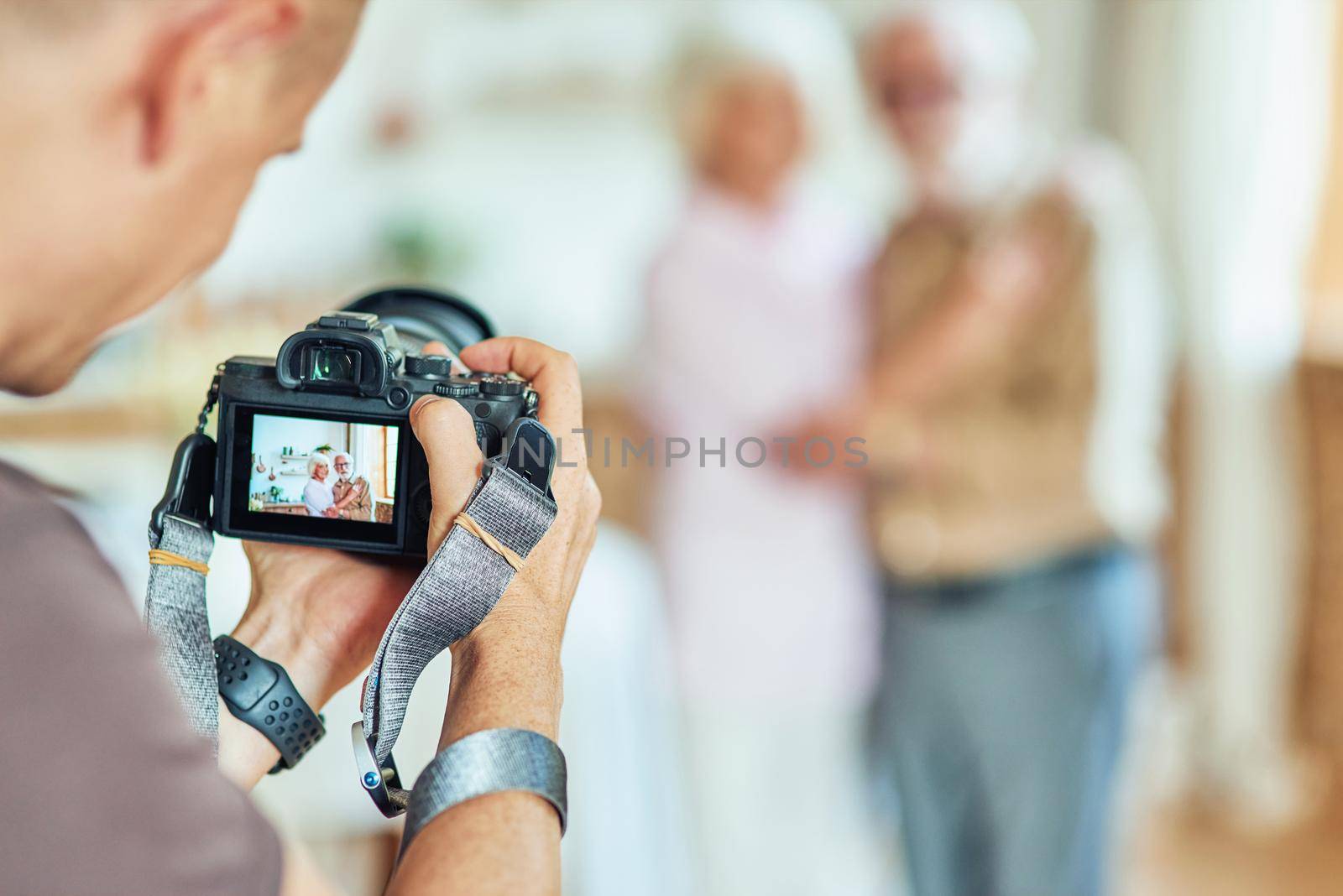 Elderly couple posing for a photographer at their home. Focus on camera. Lifestyle concept