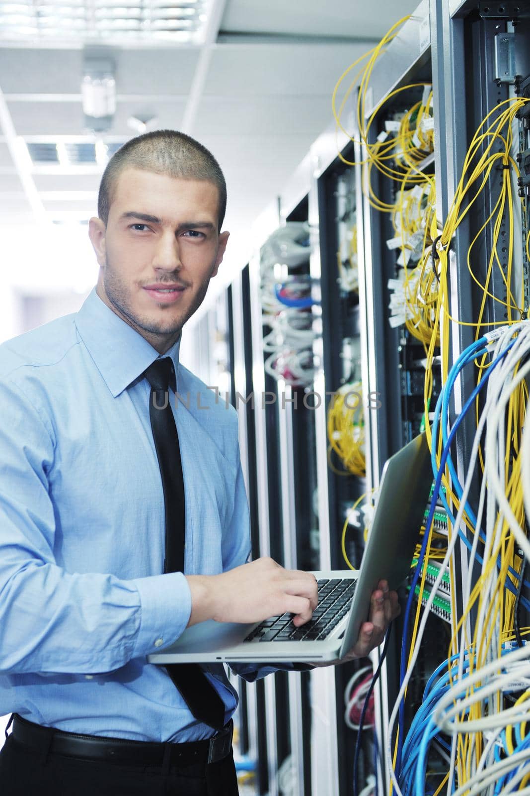 young engeneer business man with thin modern aluminium laptop in network server room