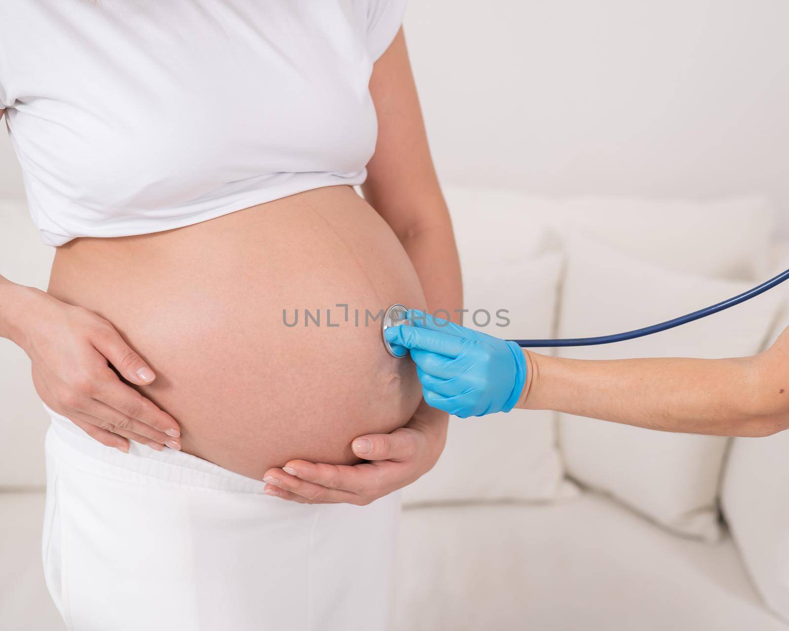 The doctor listens with a phonendoscope to the heartbeat in the belly of a pregnant woman