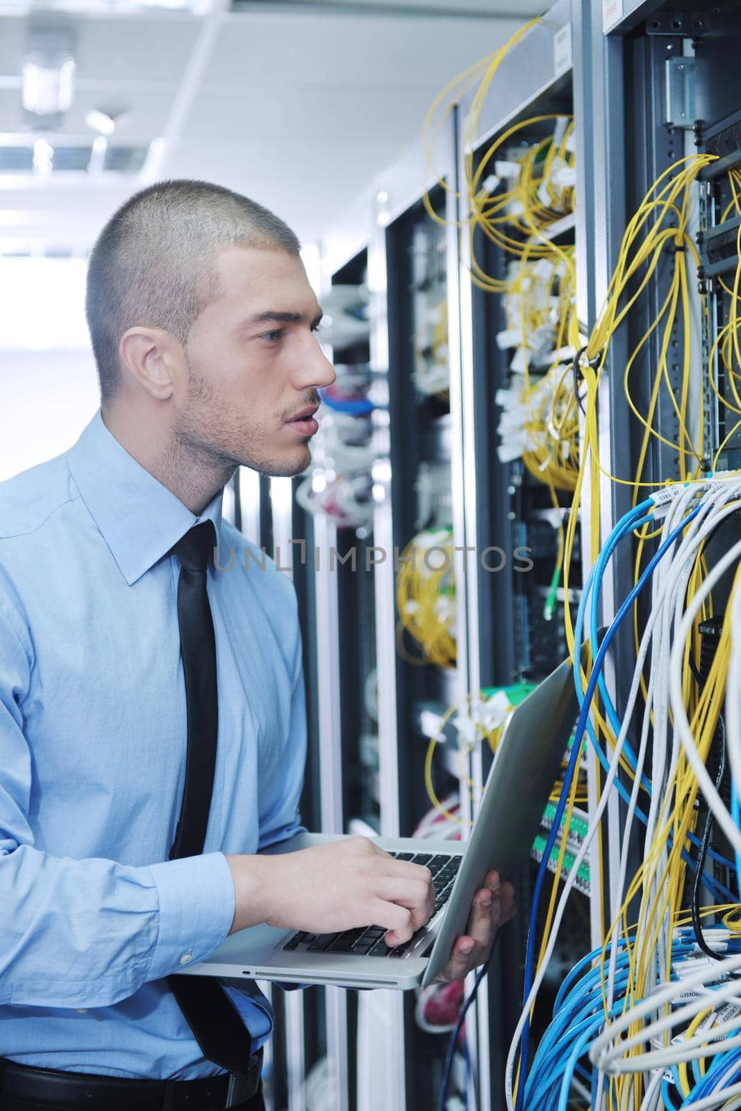 young engeneer business man with thin modern aluminium laptop in network server room