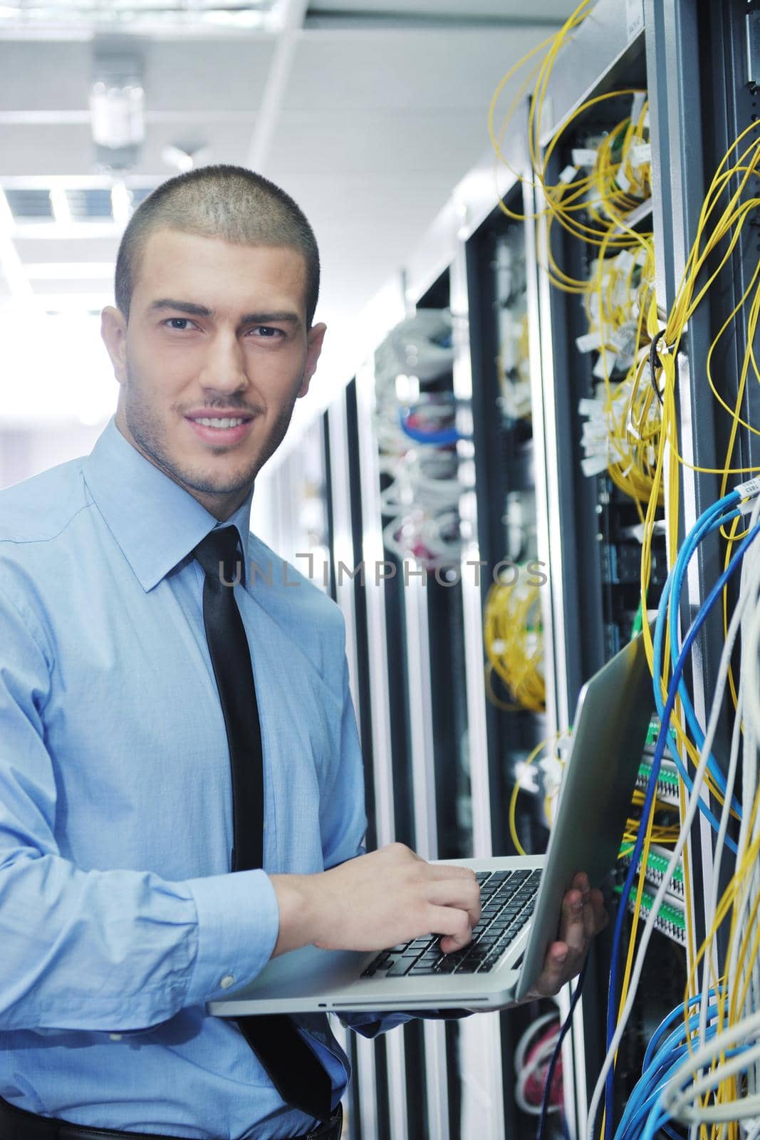 young engeneer business man with thin modern aluminium laptop in network server room