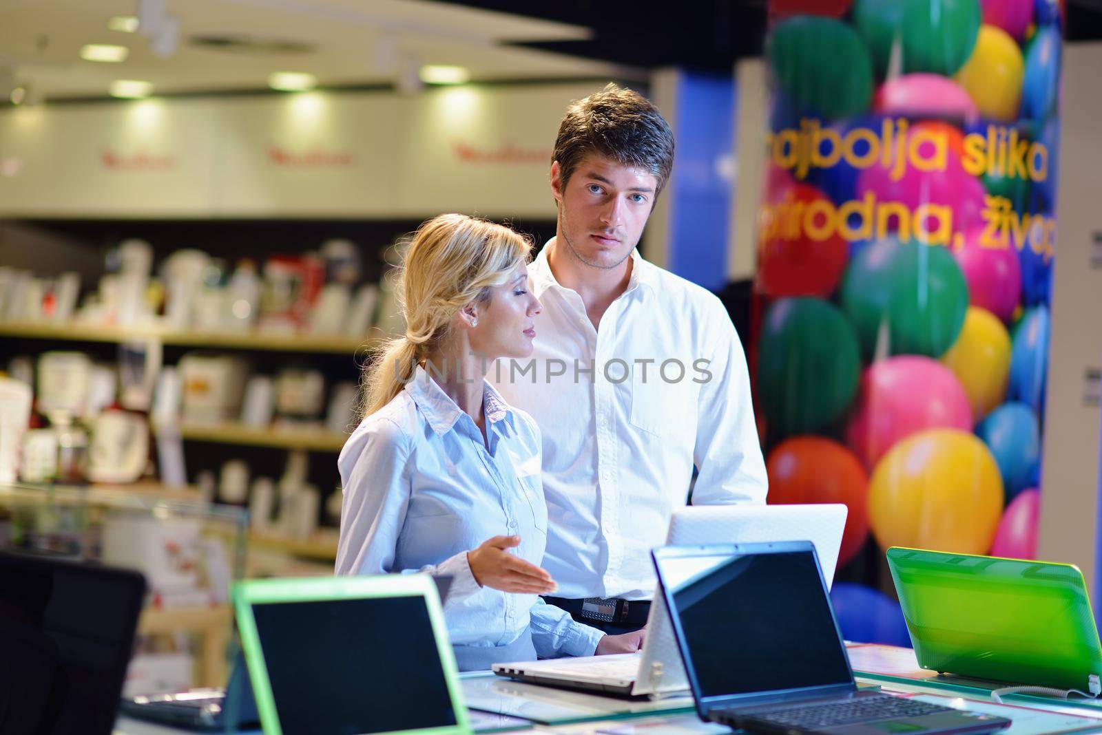 people in consumer electronics  retail store looking at latest laptop, television and photo camera to buy