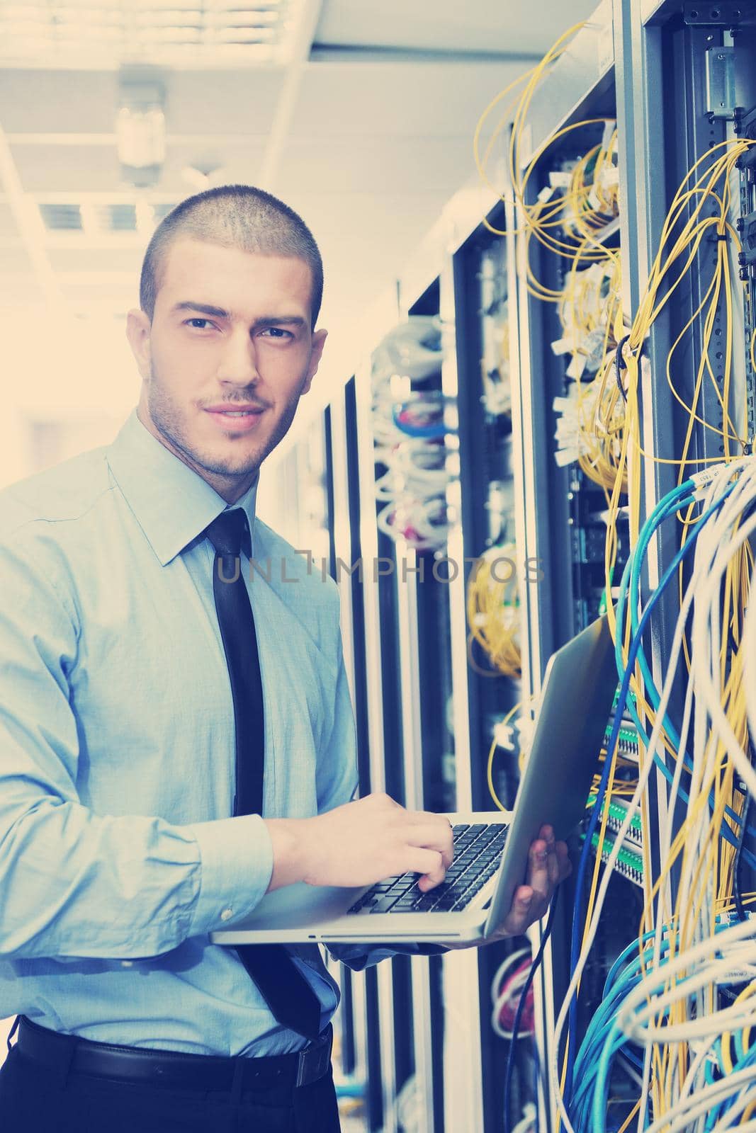 young engeneer business man with thin modern aluminium laptop in network server room