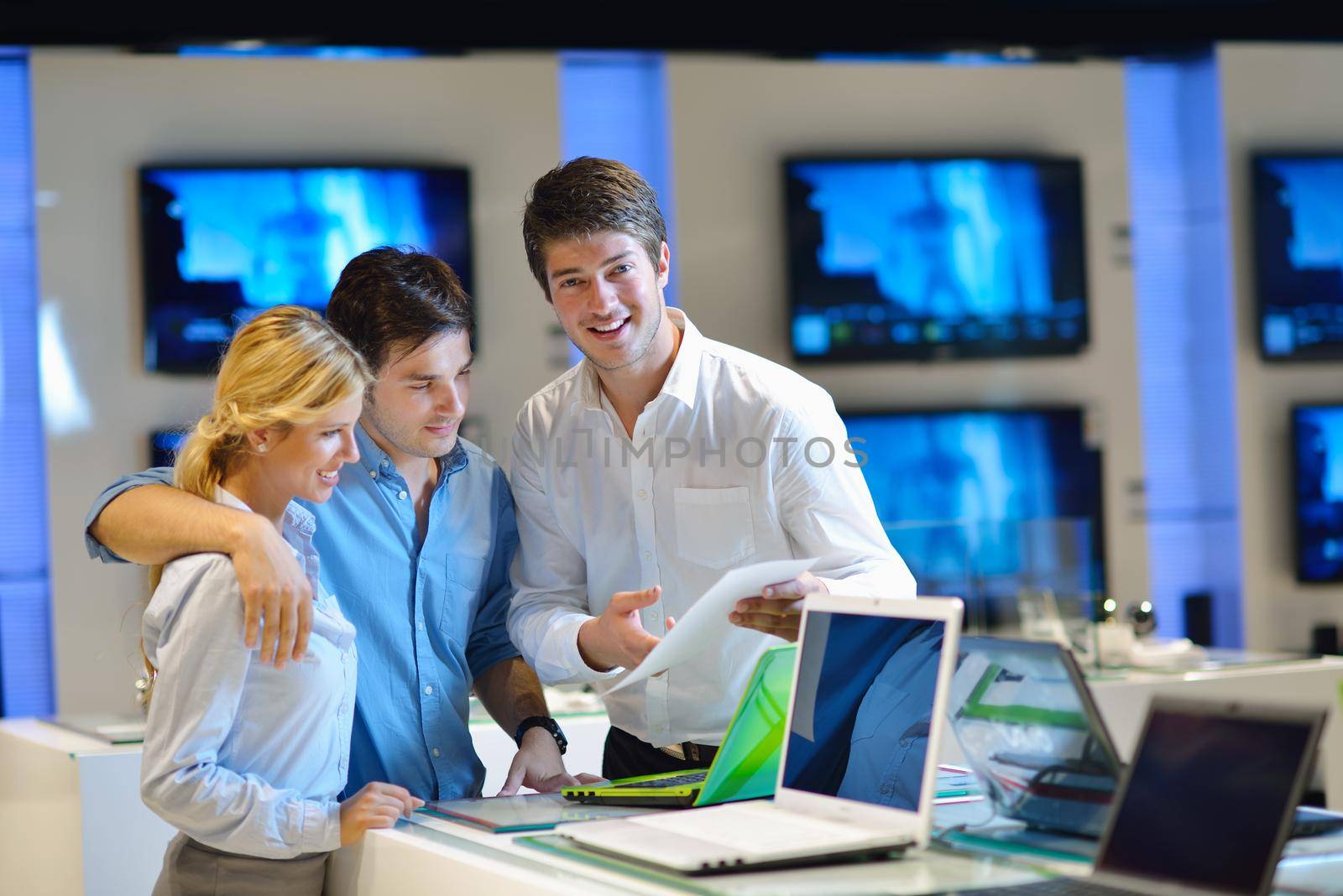 Young couple in consumer electronics store looking at latest laptop, television and photo camera