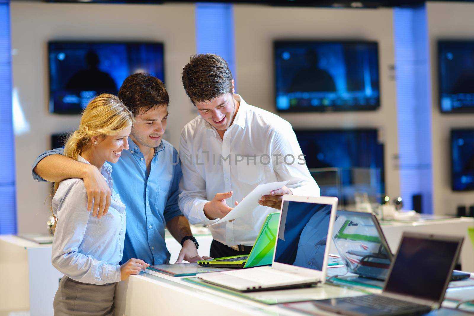 Young couple in consumer electronics store looking at latest laptop, television and photo camera