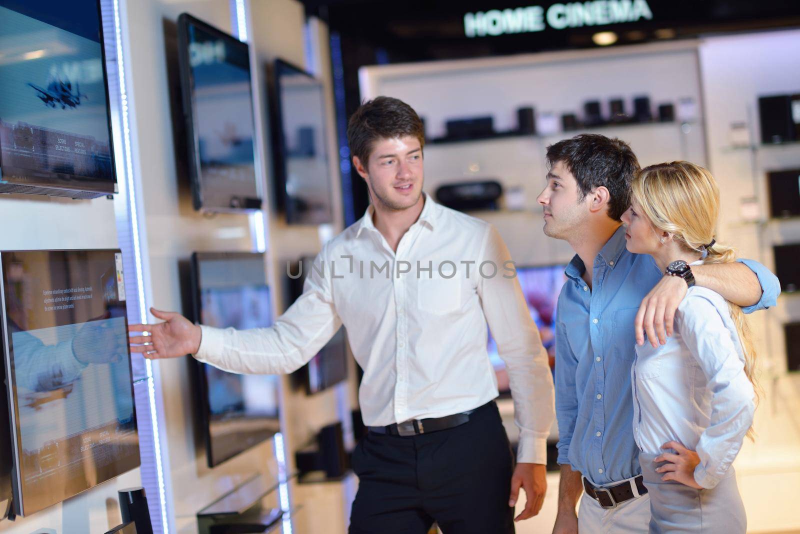people in consumer electronics  retail store looking at latest laptop, television and photo camera to buy