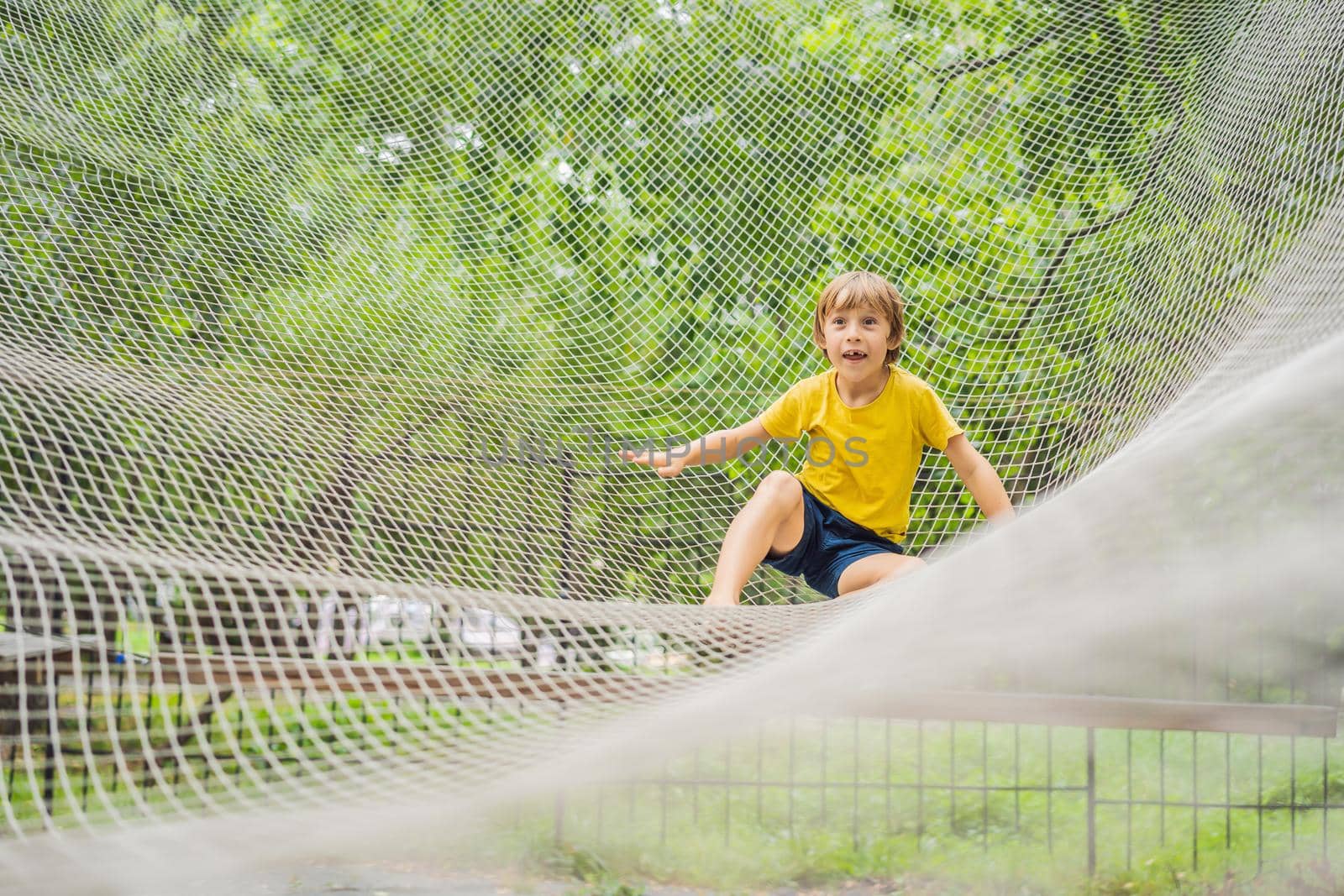 practice nets playground. boy plays in the playground shielded with a protective safety net. concept of children on line, kid in social networks. blurred background, blurred motion due to the concept by galitskaya