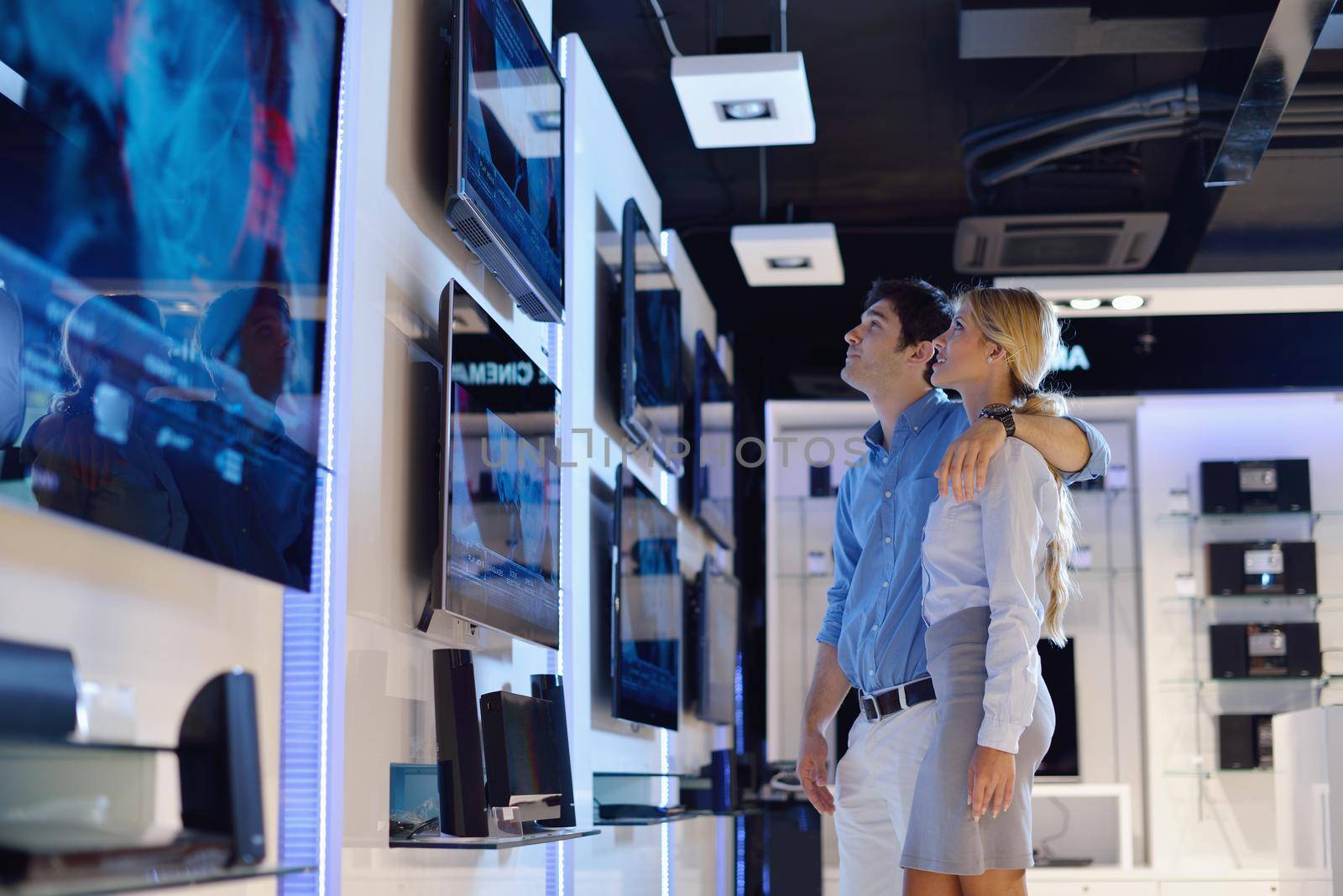 people in consumer electronics  retail store looking at latest laptop, television and photo camera to buy