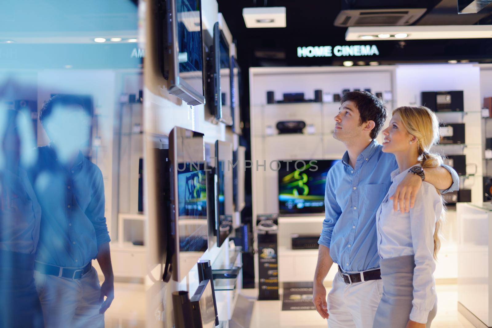 people in consumer electronics  retail store looking at latest laptop, television and photo camera to buy