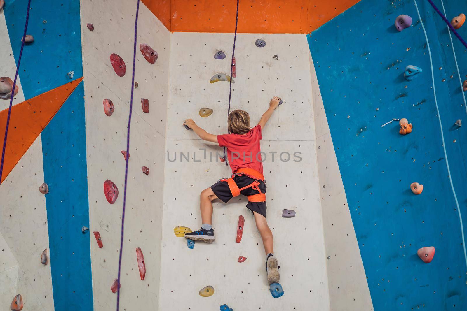 Boy at the climbing wall without a helmet, danger at the climbing wall by galitskaya
