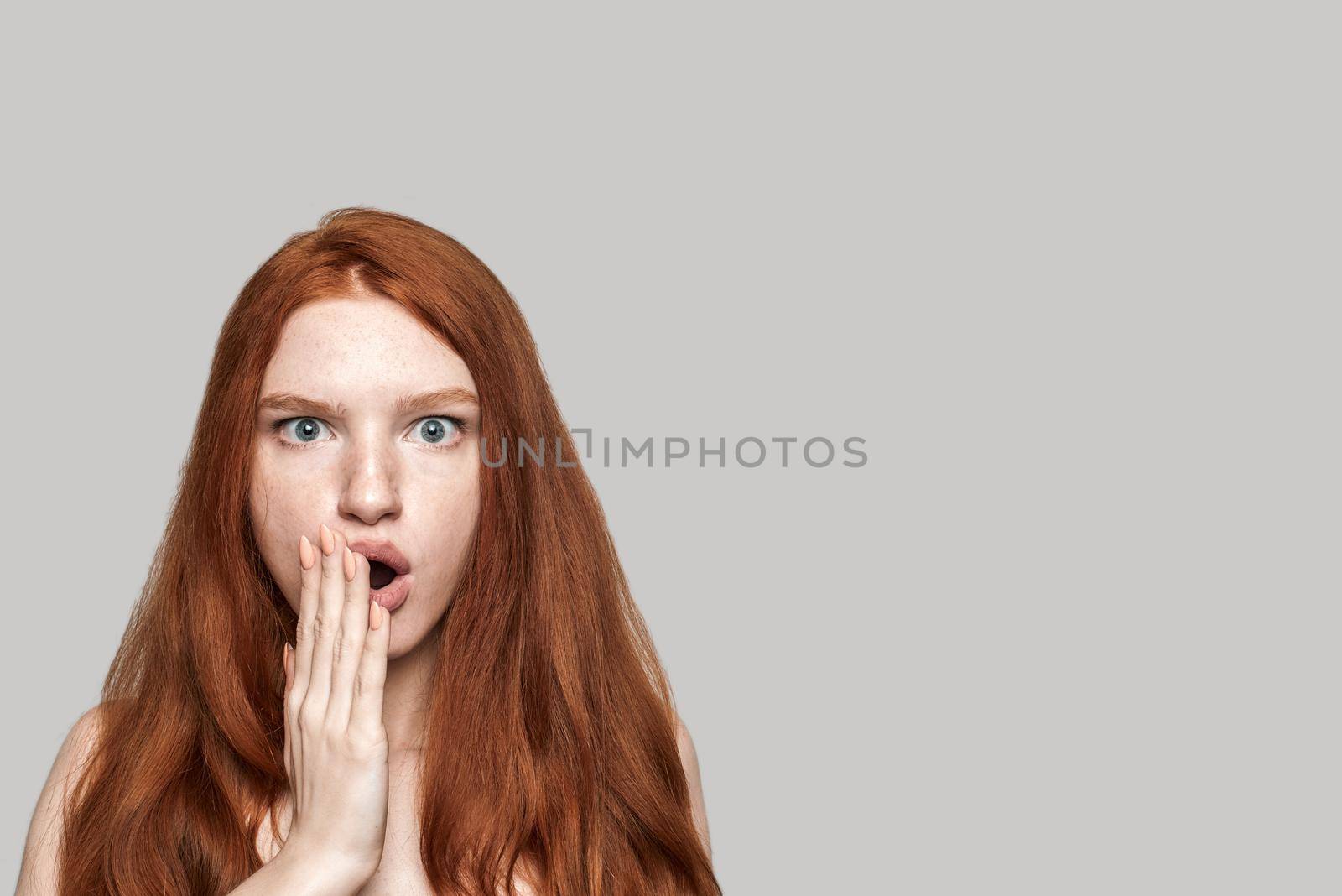 I don't believe Studio shot of cute redhead surprised girl making shocked face while standing against grey background. Human emotions