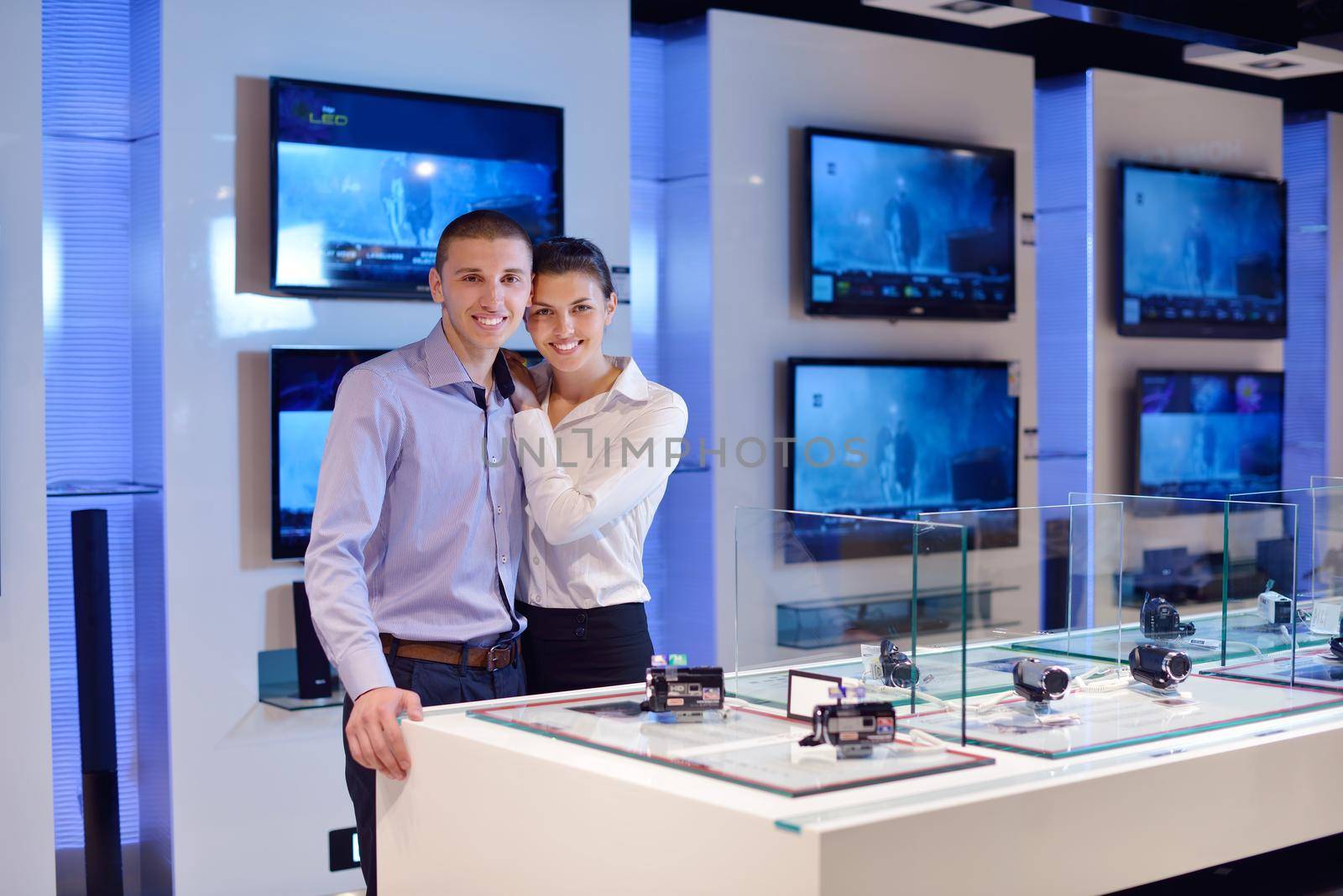 people in consumer electronics  retail store looking at latest laptop, television and photo camera to buy