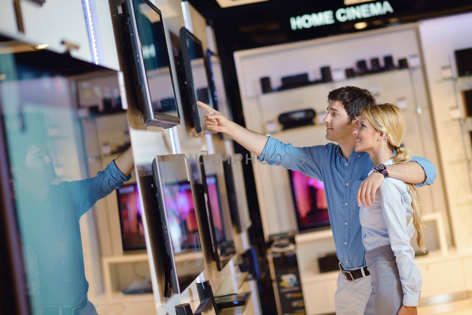 people in consumer electronics  retail store looking at latest laptop, television and photo camera to buy