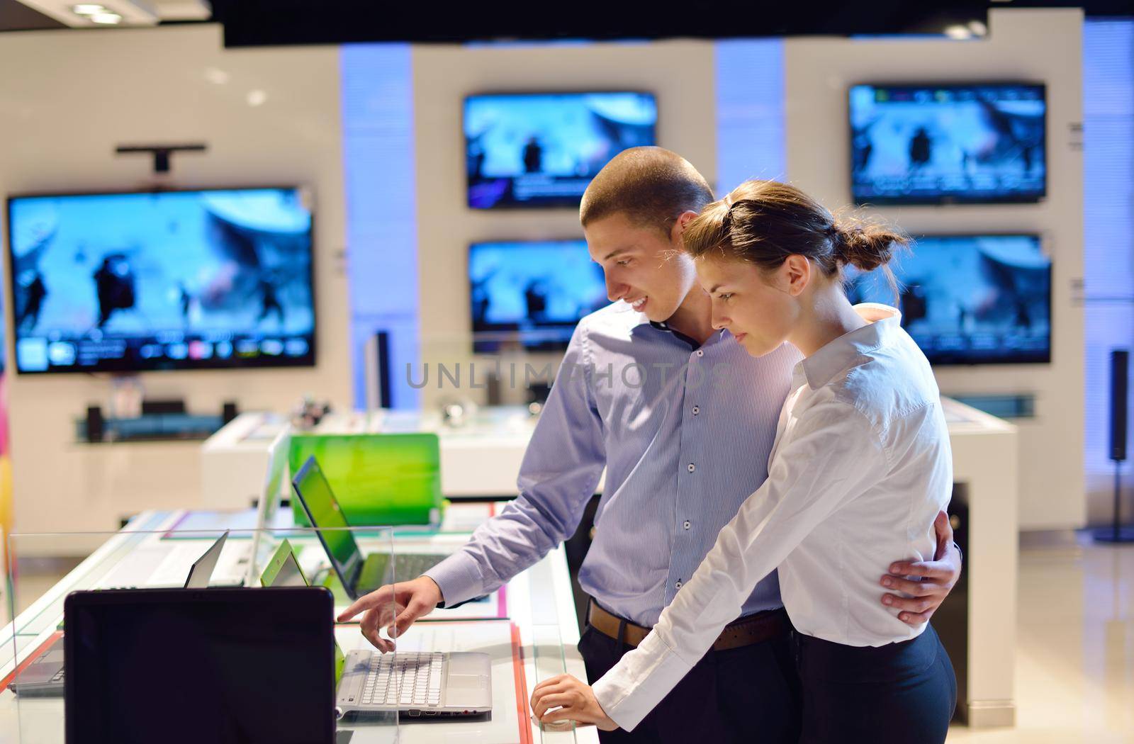 people in consumer electronics  retail store looking at latest laptop, television and photo camera to buy