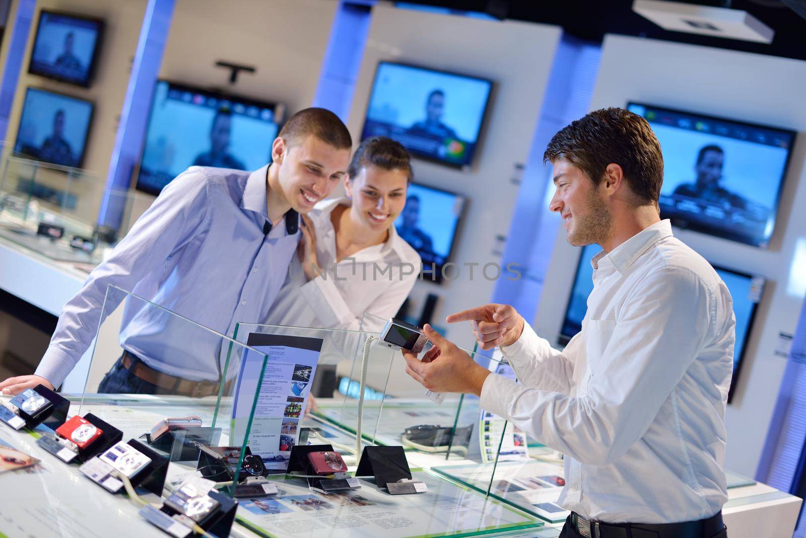 people in consumer electronics  retail store looking at latest laptop, television and photo camera to buy