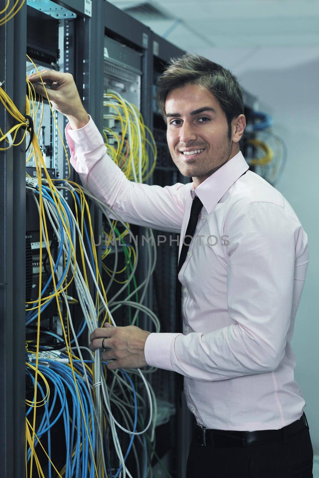 young it engineer in datacenter server room by dotshock