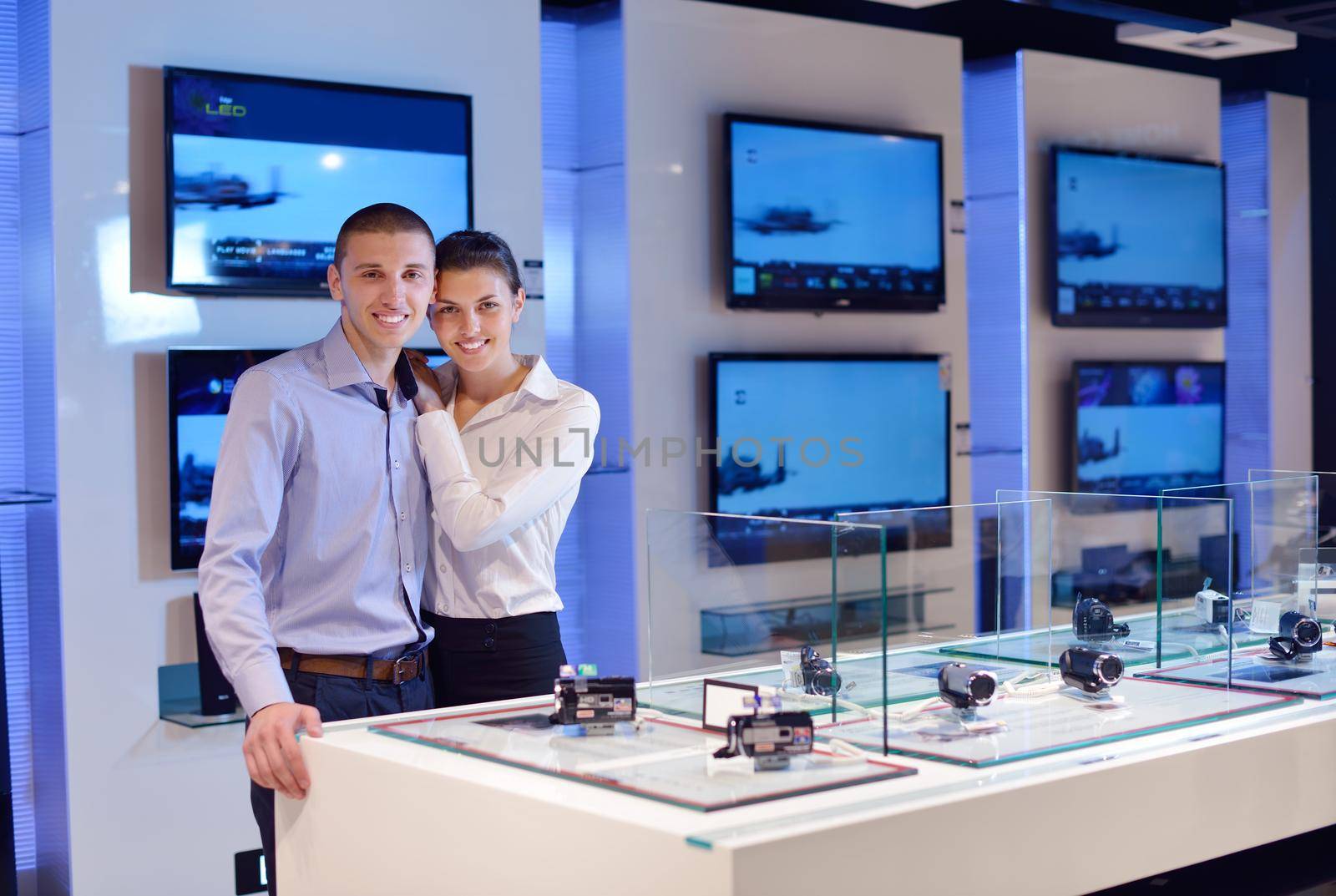 people in consumer electronics  retail store looking at latest laptop, television and photo camera to buy