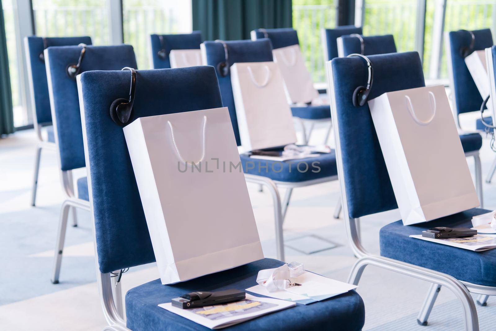 interior of big modern conference room with gifts and headphones on chairs for participants before starting a business seminar