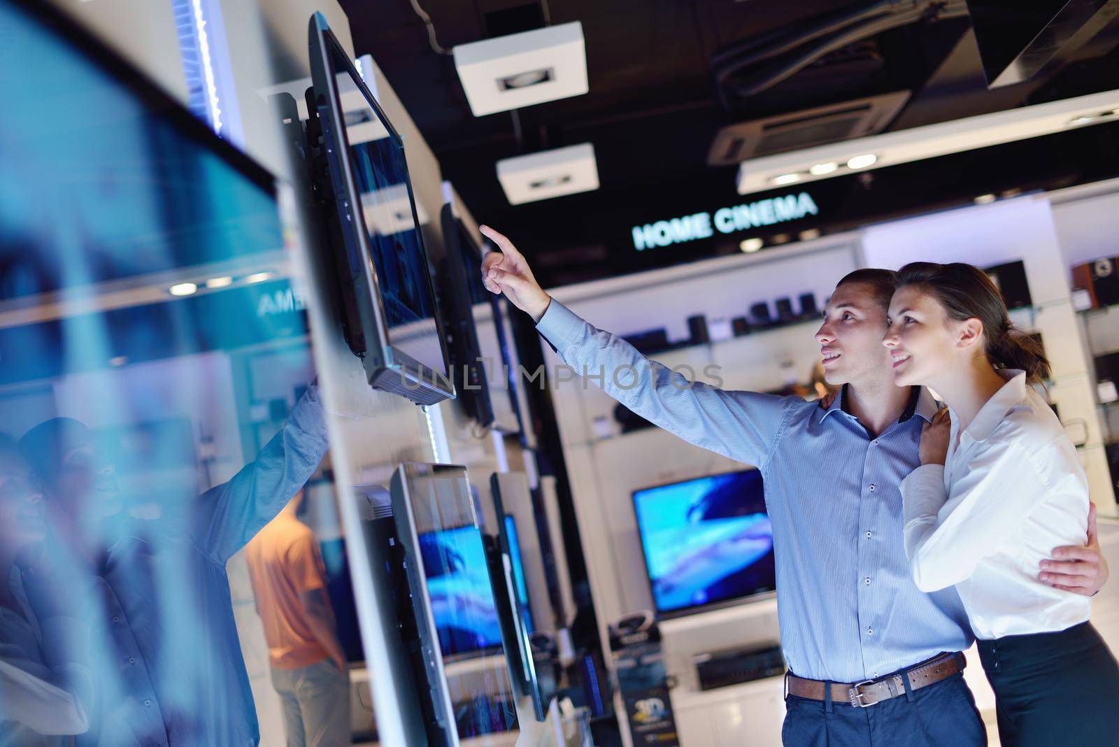 people in consumer electronics  retail store looking at latest laptop, television and photo camera to buy