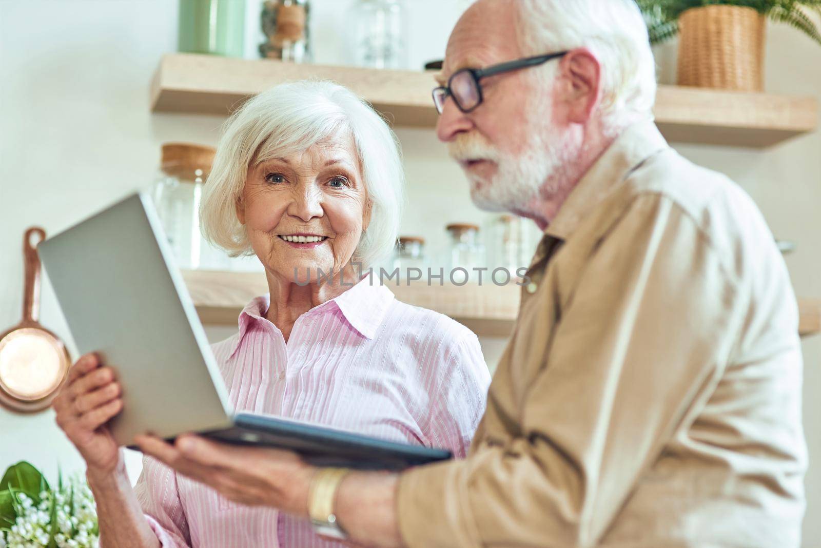 Senior couple holding computer on the kitchen by friendsstock