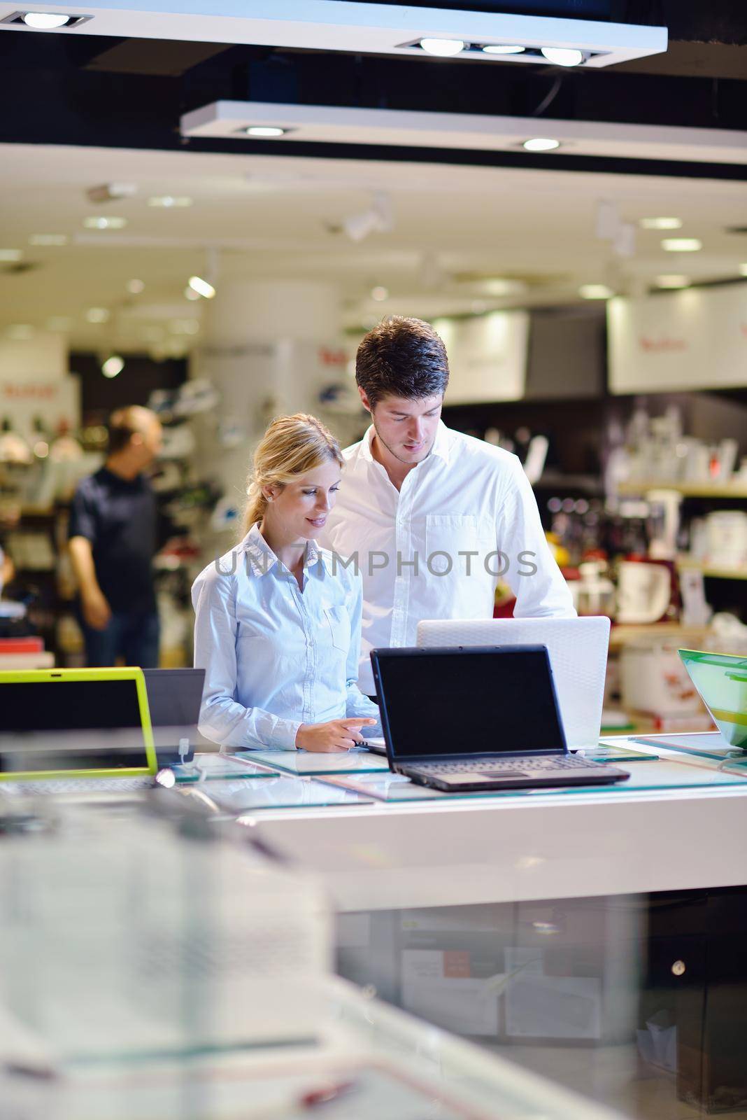 people in consumer electronics  retail store looking at latest laptop, television and photo camera to buy