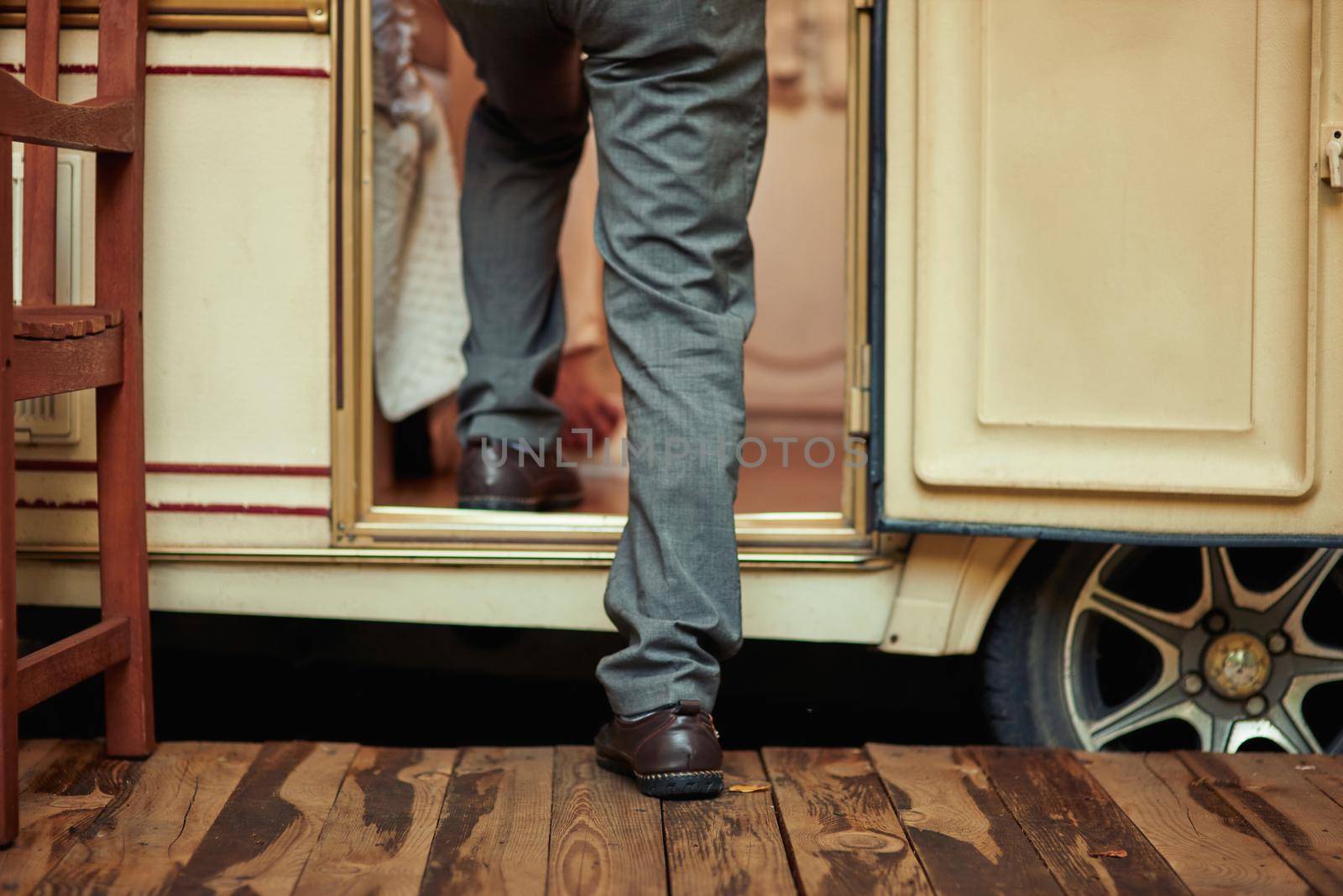 Cropped photo of senior man entering his camper man while crossing the threshold. Travel concept