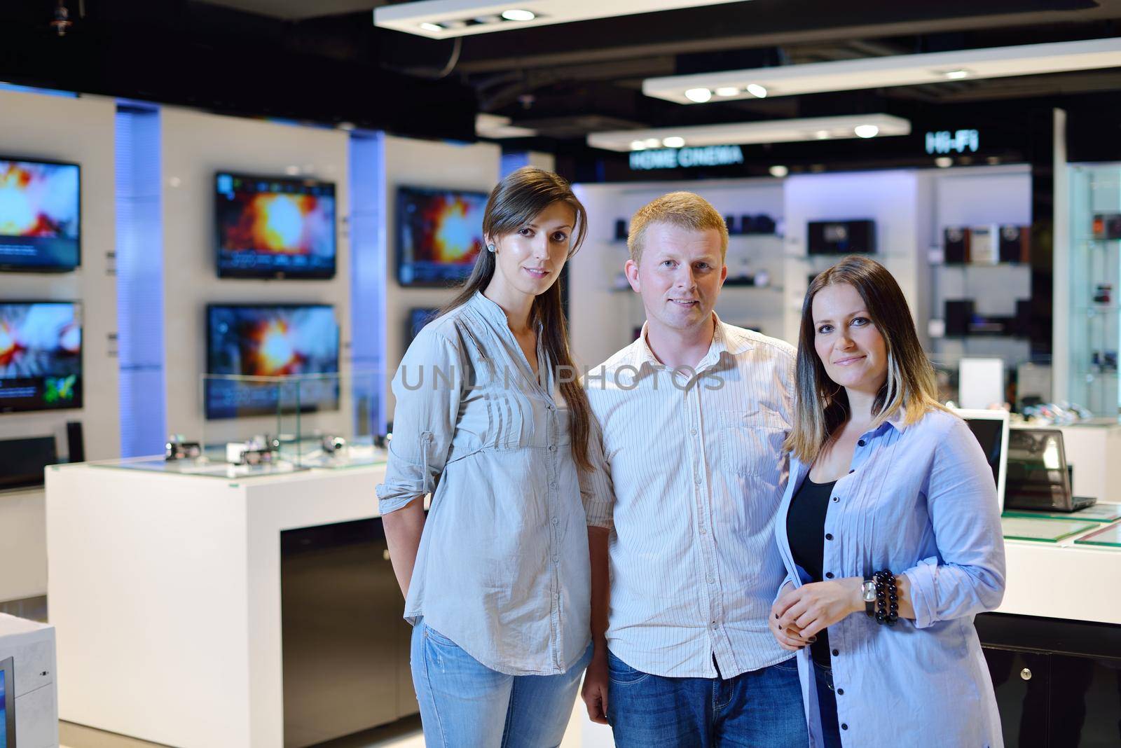 people in consumer electronics  retail store looking at latest laptop, television and photo camera to buy