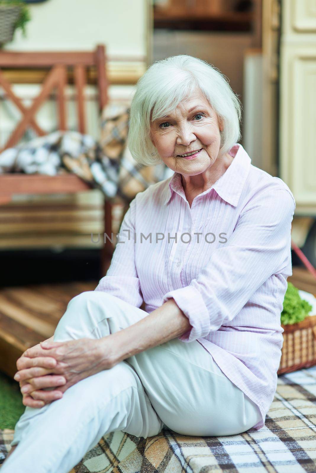 Happy beautiful senior woman sitting on on the van porch outdoors. Lifestyle concept