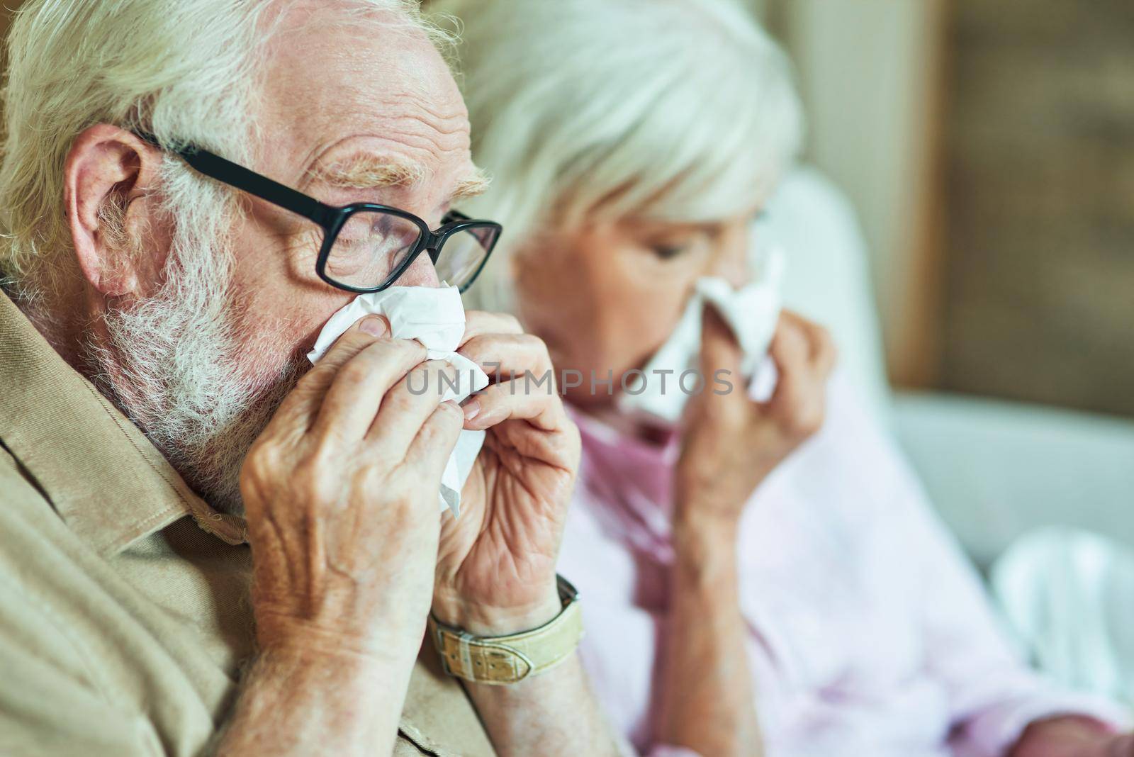 Close up of elderly man and woman with a runny nose using paper napkins. Care and health concept