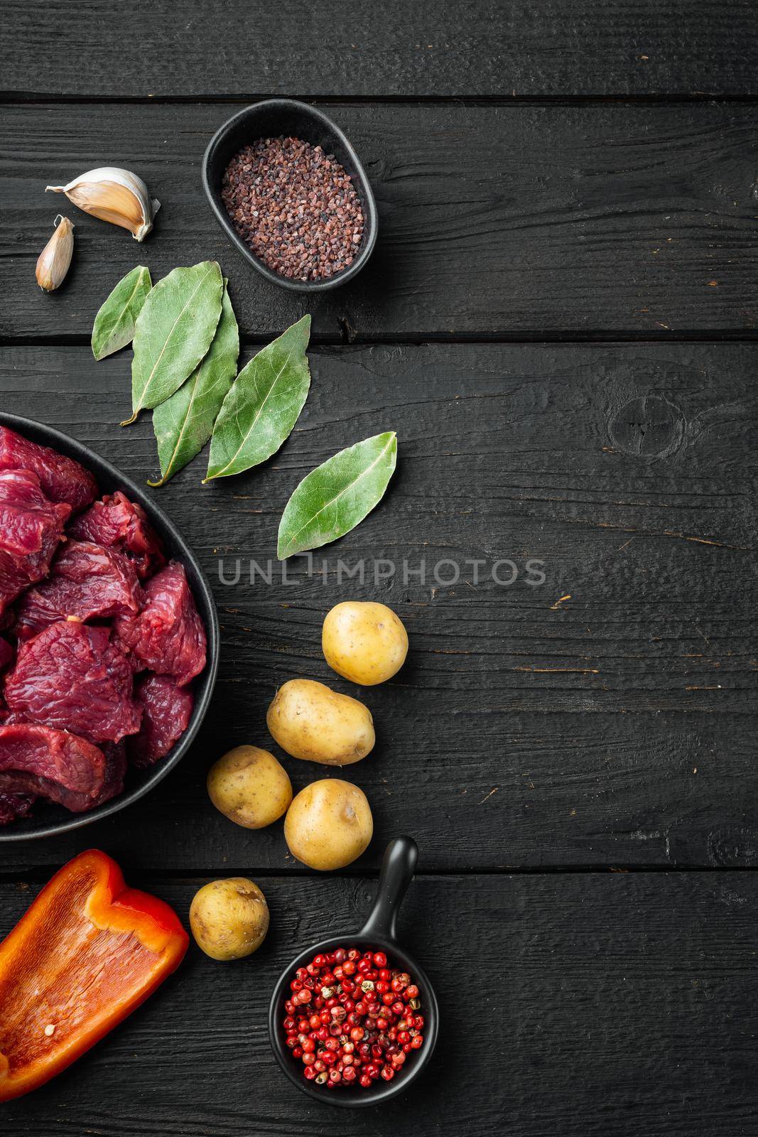 Beef stew raw ingredients set and potatoe, on black wooden background, top view flat lay, with copy space for text